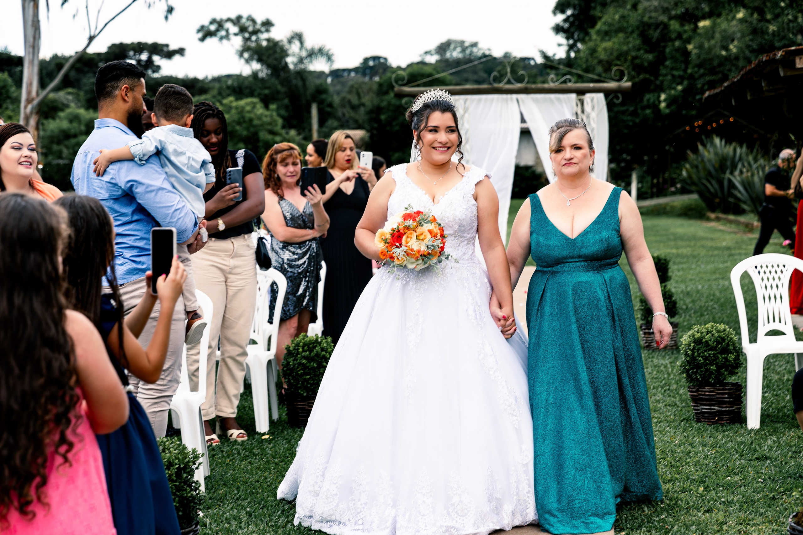 Entrada da noiva acompanhada da mãe na cerimônia de casamento, momento forte e emocionante.