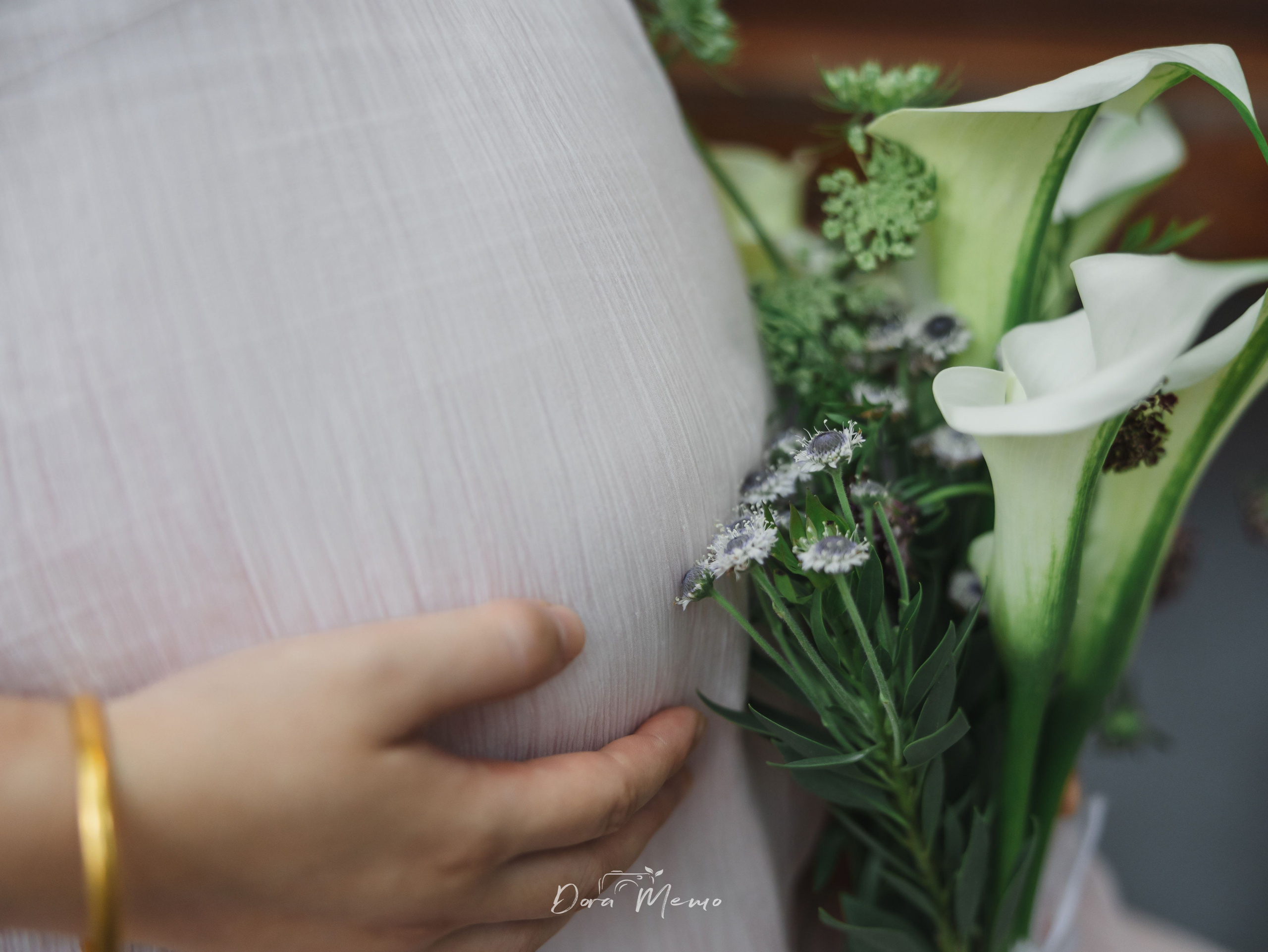 Close-up detail of a pregnant belly and bouquet, photographed by a Shanghai family photographer in a gentle maternity documentary style.