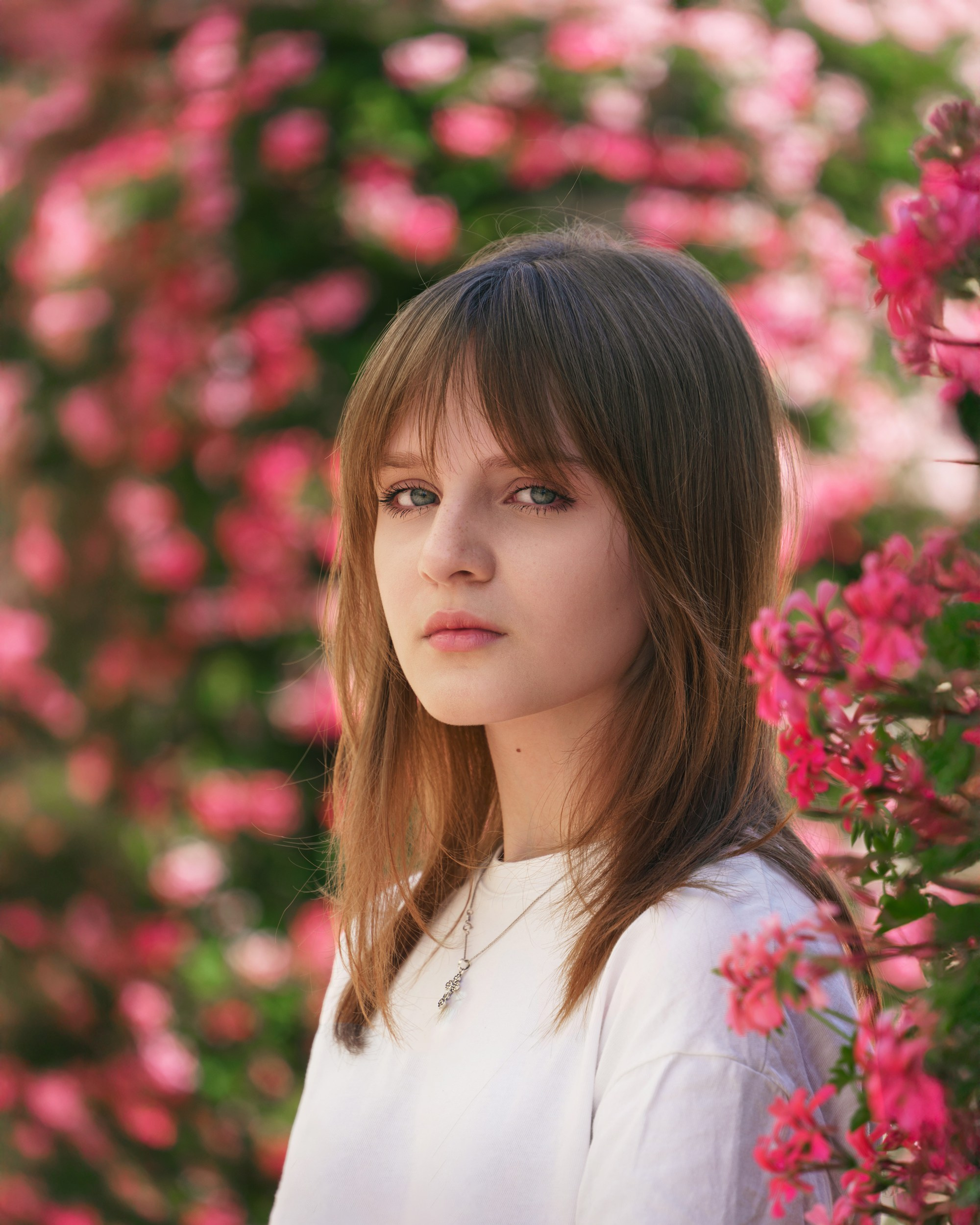 Female portrait among pink flowers, outdoor artistic portrait photography