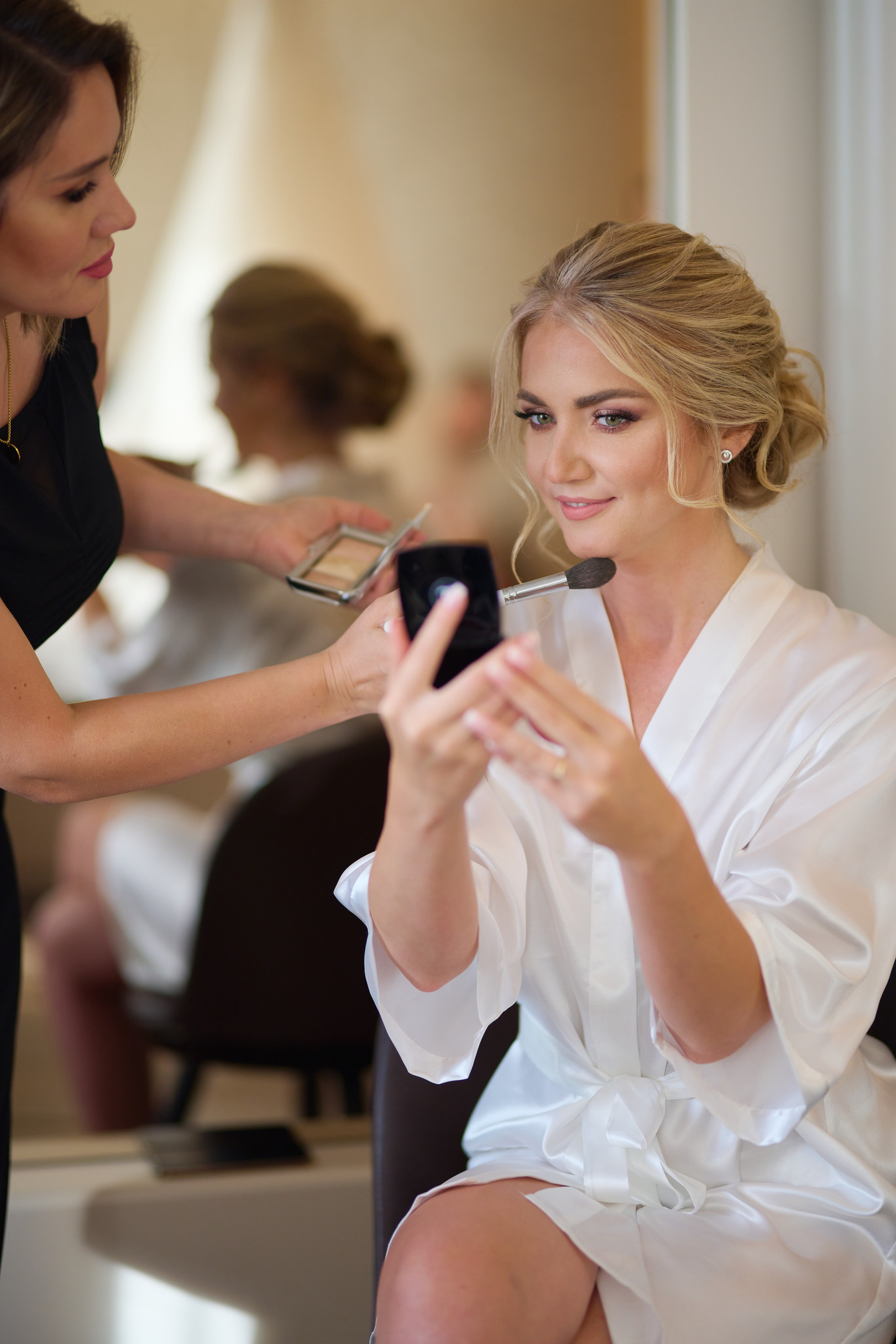 Viktoria beim Getting Ready in Karlsruhe – ihre Brautjungfern helfen liebevoll beim Ankleiden vor dem Spiegel im Hotelzimmer.