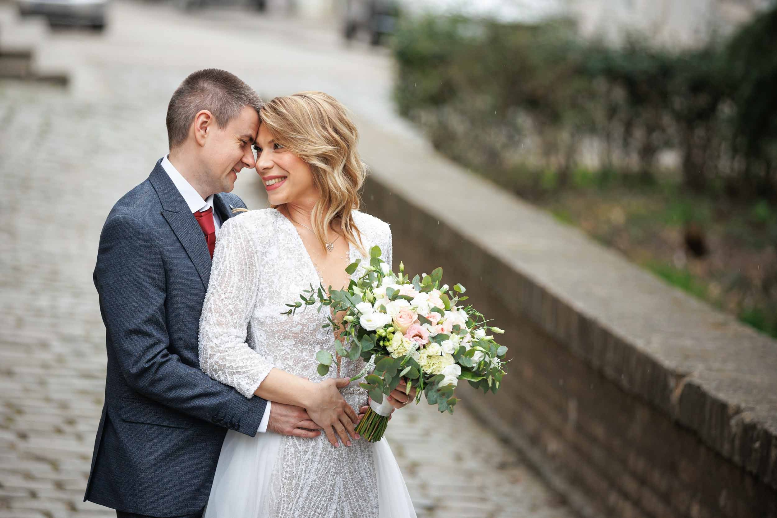 Portret nasmejanih mladenaca, mlada sa bidermajerom i mladoženja u sivom odelu, spontana wedding fotografija.