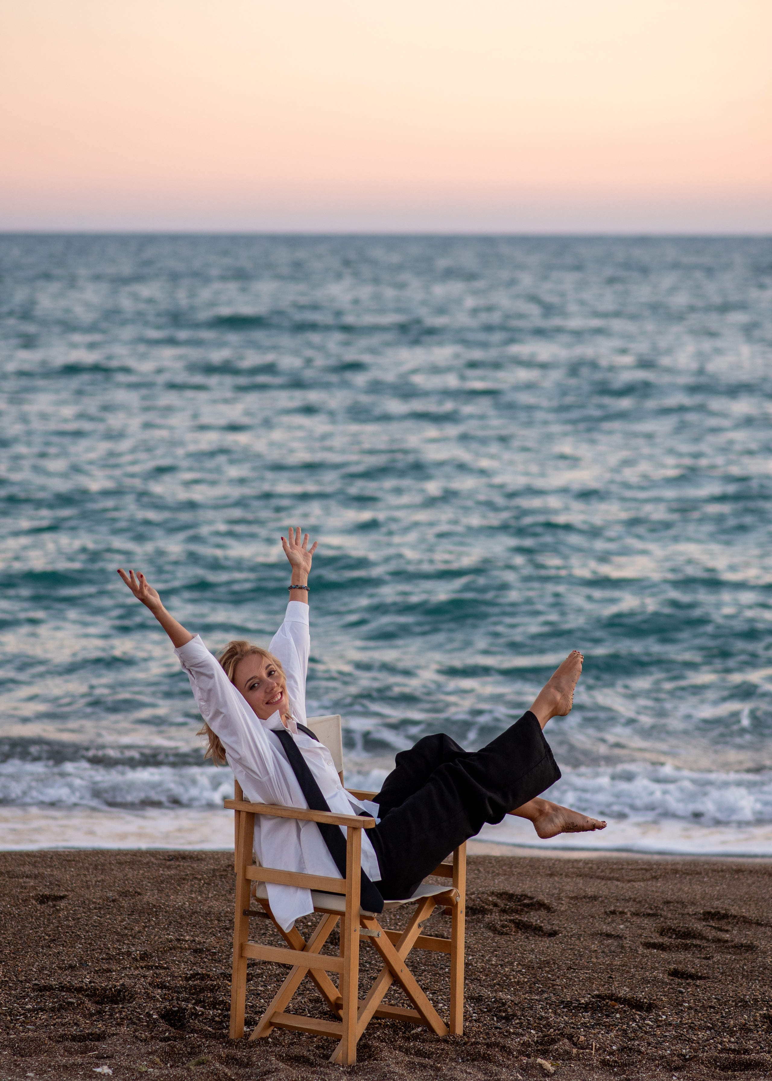 Портрет девушки в движении на стуле на фоне морского заката