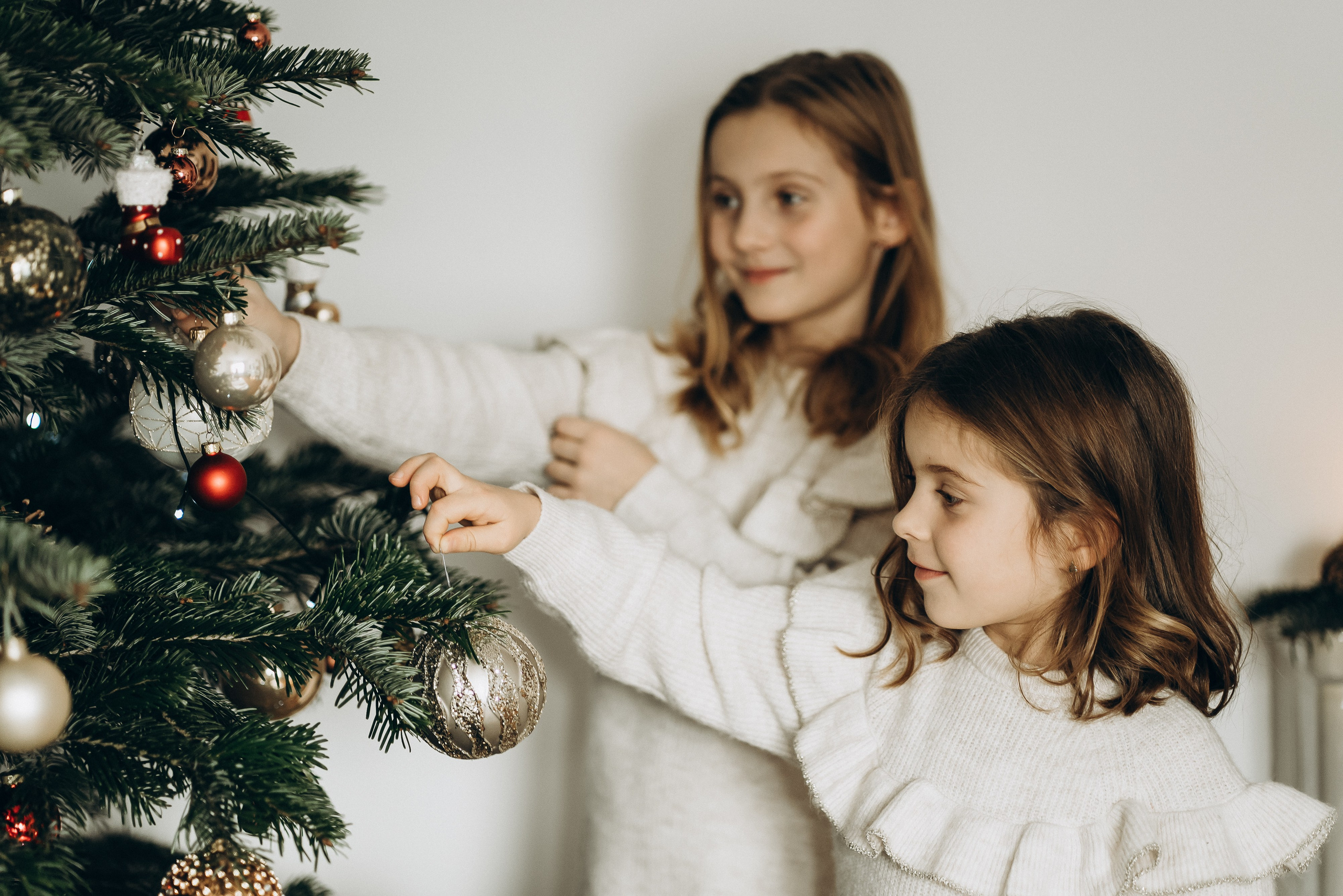 Eine liebevolle Aufnahme 2 Schwester, die gemeinsam den Weihnachtsbaum schmücken.
