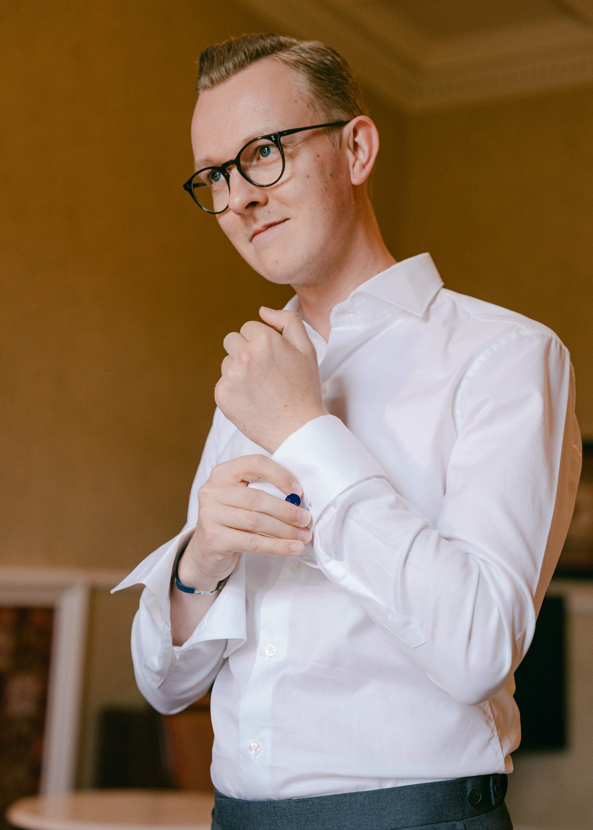 Groom in white dress shirt adjusting cufflinks, getting ready for luxury wedding at Villa Rothschild Frankfurt