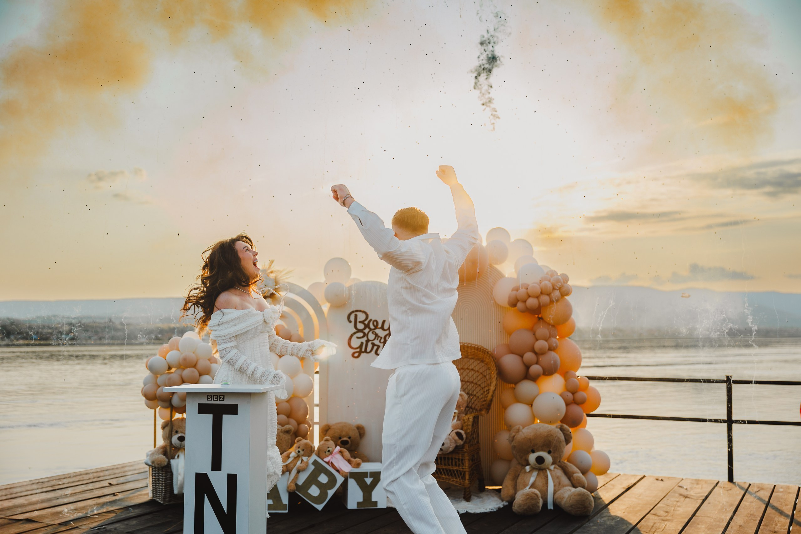 Cuplu dansând de bucurie după gender reveal cu lumină aurie