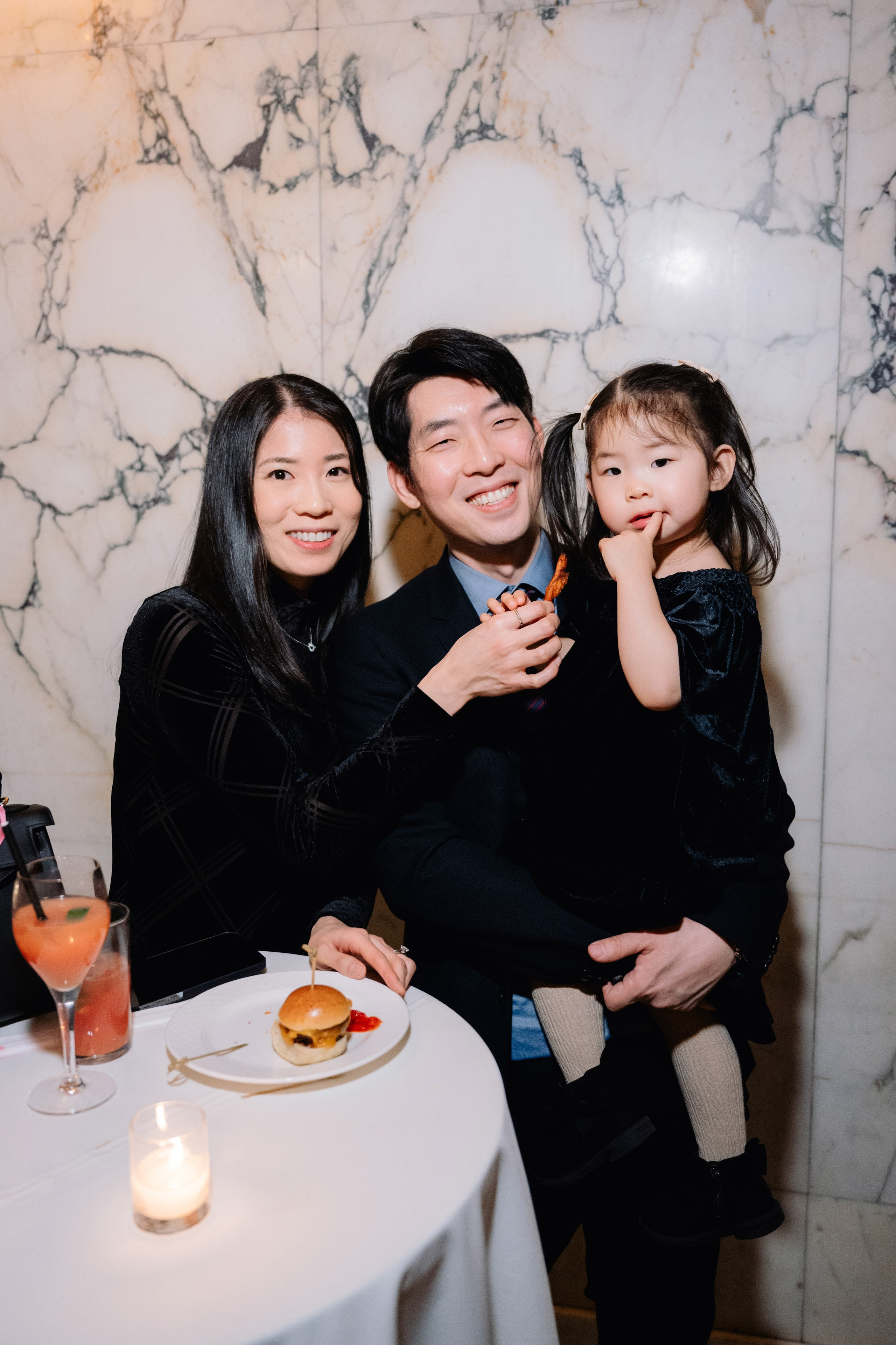 a man and woman holding a child at a table