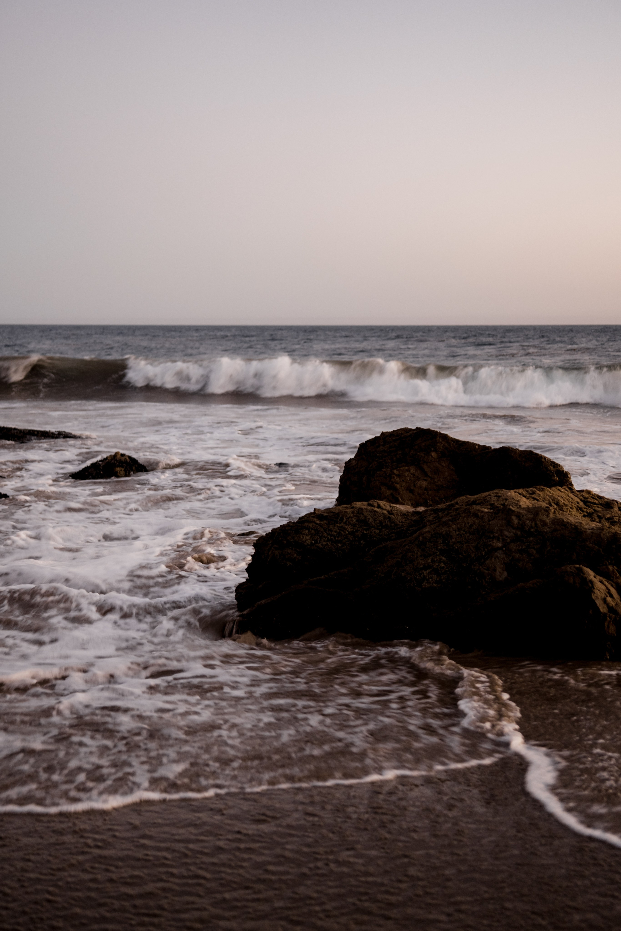 Waves gently rolling onto the sand during sunset, creating a peaceful coastal atmosphere.