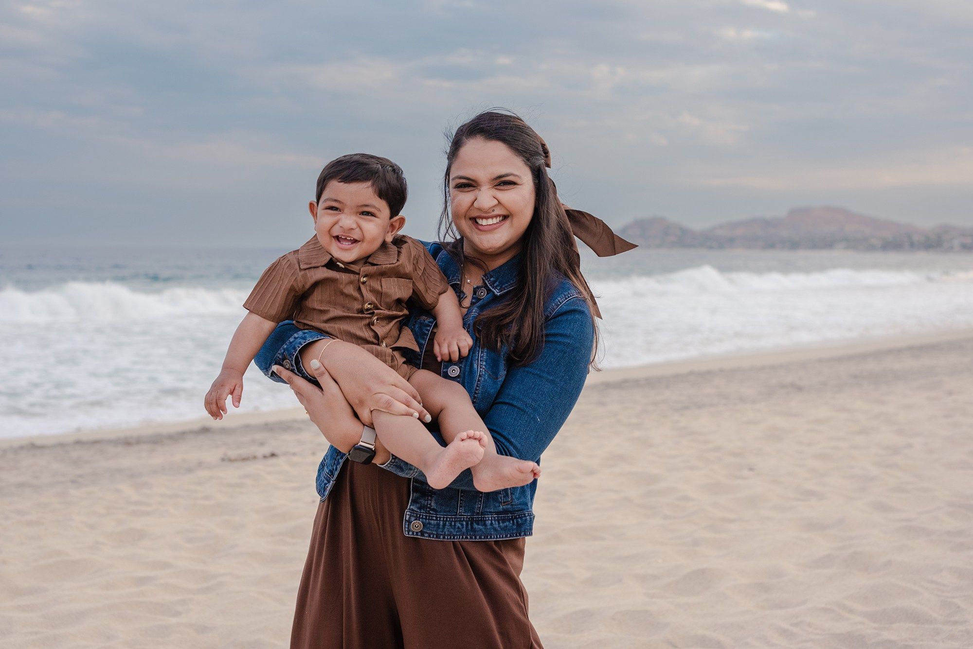 Mother carrying her toddler son while walking on the beach at Hyatt Ziva Los Cabos