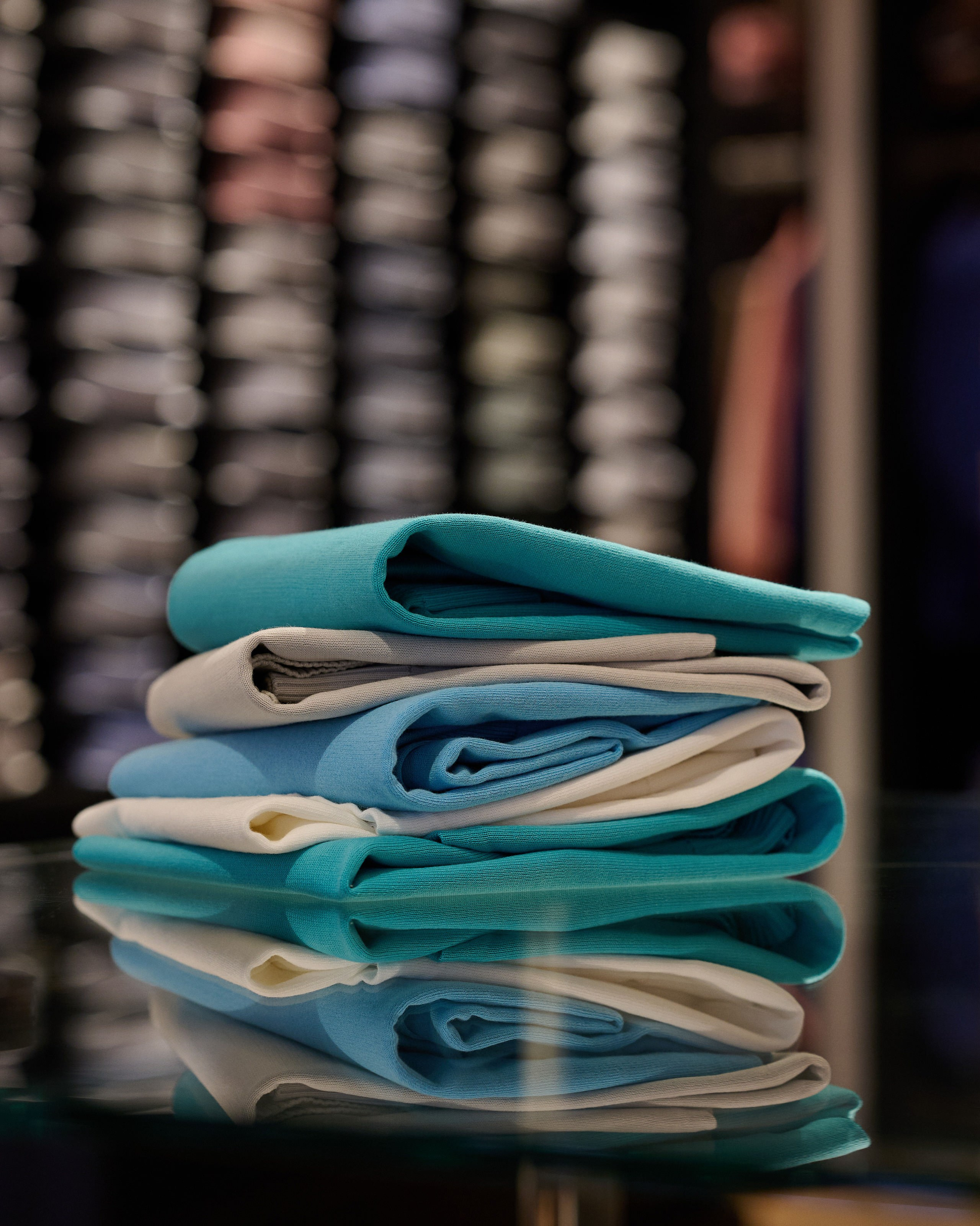 Produktfotografie Wien – Gefaltete Einstecktücher und Krawatten in Pastelltönen auf Glastisch.