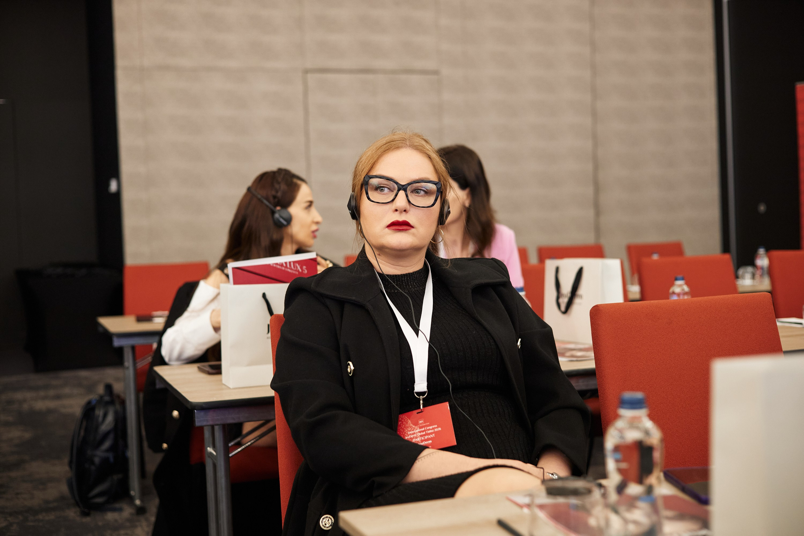 Крупный план лица участника, вовлеченного в доклад спикера на официальном форуме.