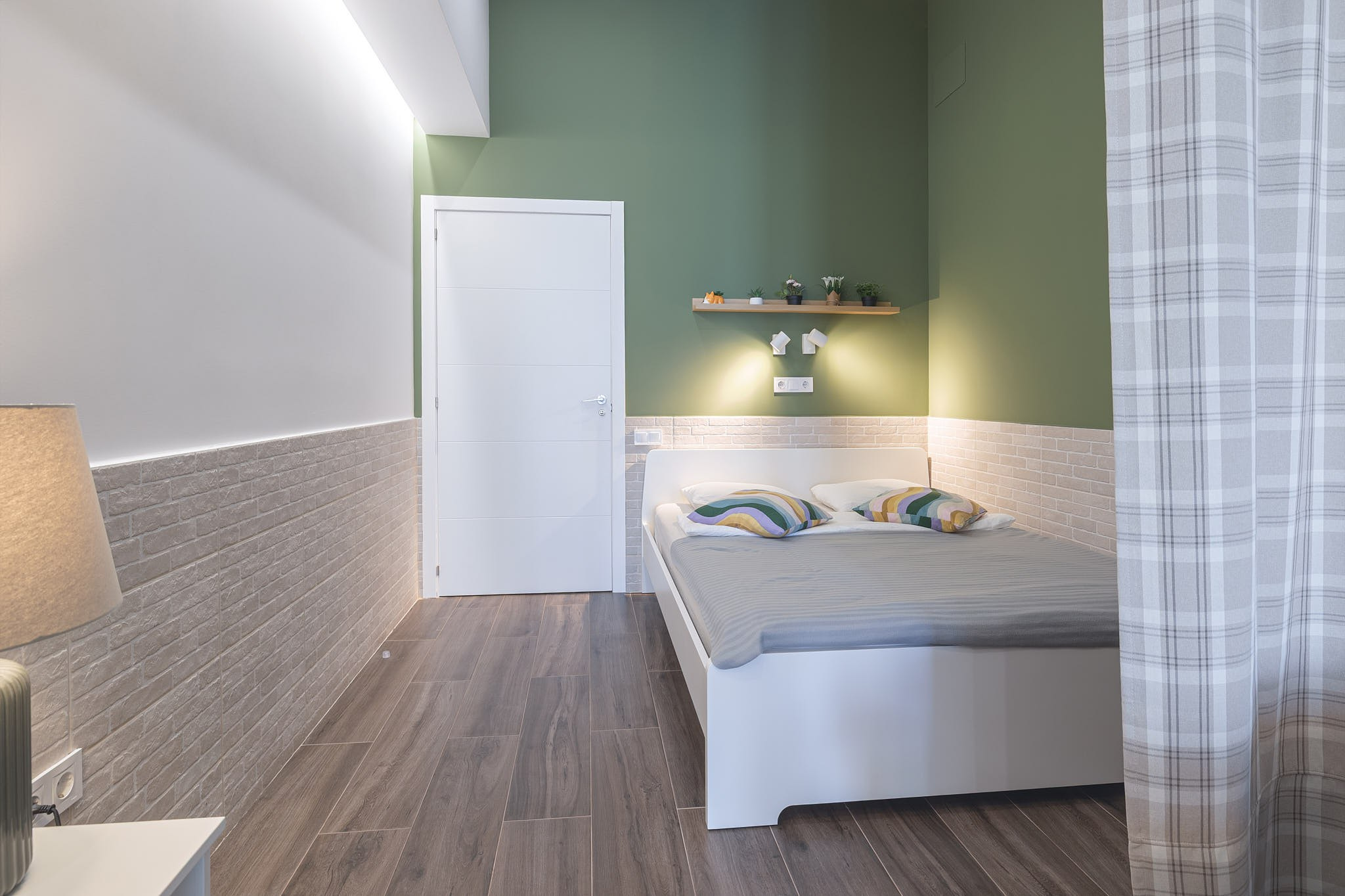 dormitorio con pared verde e iluminación suave en un apartamento en Valencia
