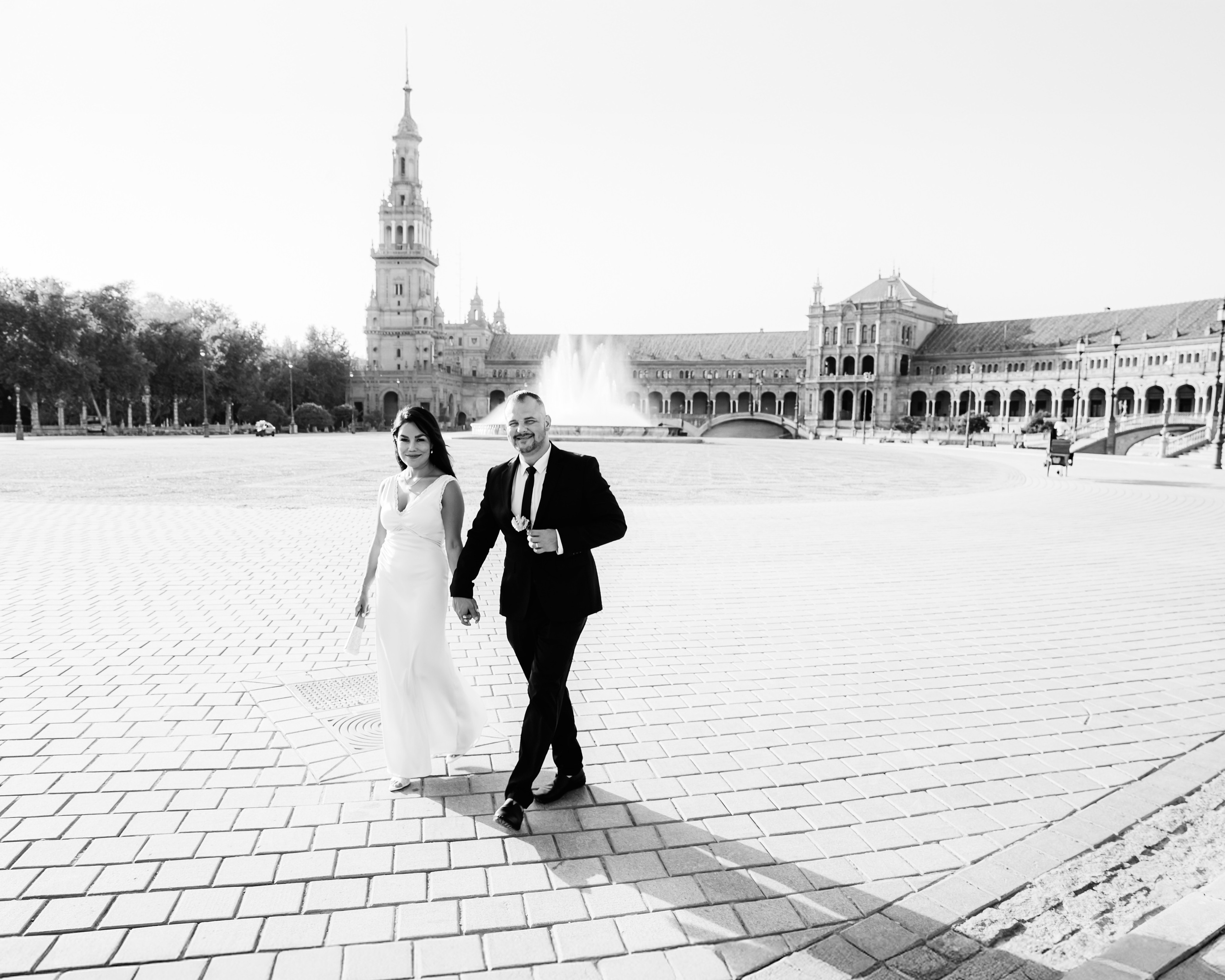Elegant black and white wedding photo of a couple walking hand in hand at Plaza de España in Sevilla, Spain — an iconic destination for romantic and cinematic wedding photoshoots in Seville and across southern Spain.