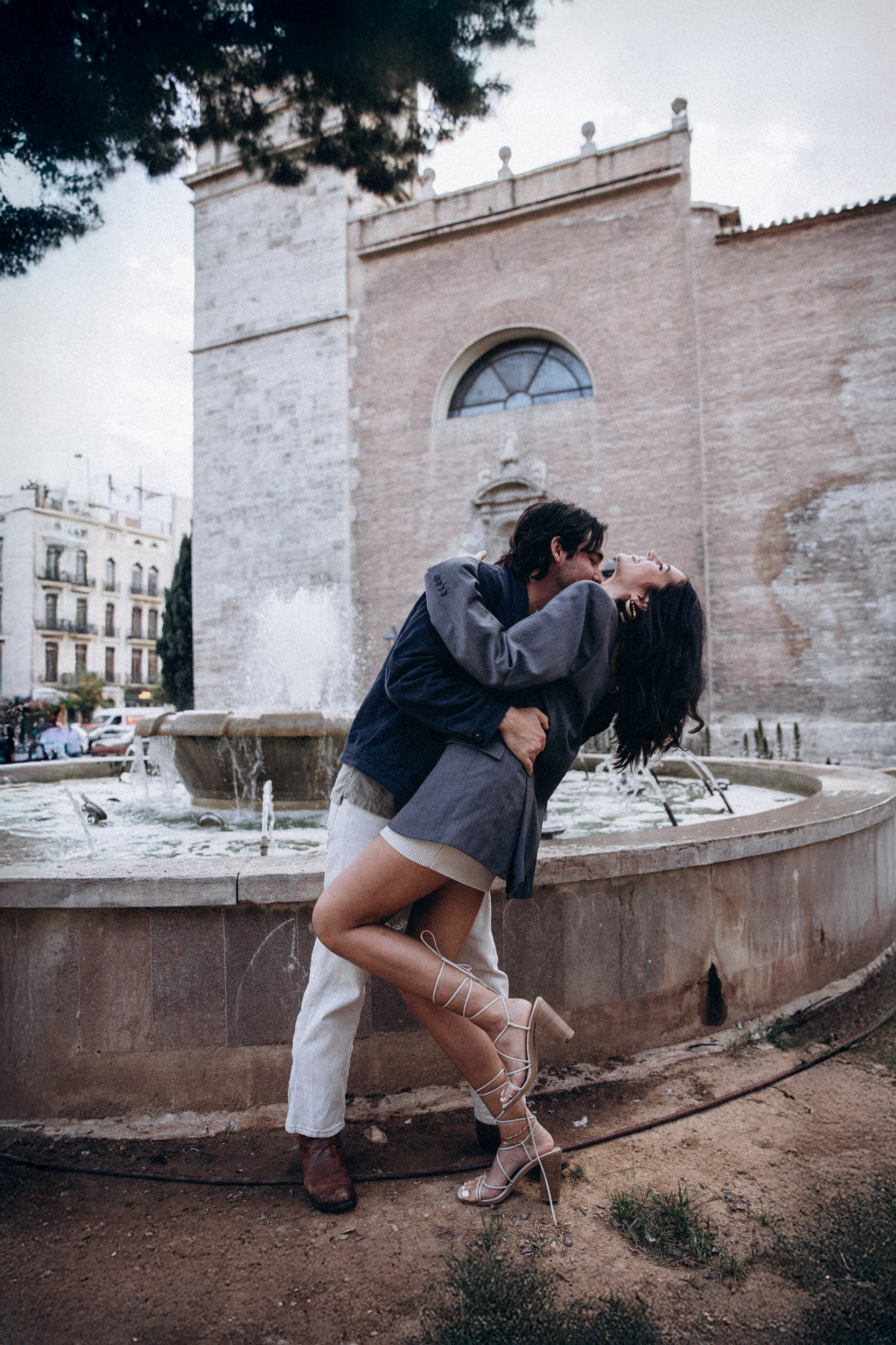 Playful couple dancing by a historic fountain in Altea, Spain — a joyful love story photoshoot capturing movement, romance, and authentic connection. Perfect for couples searching for creative and emotional couple photography sessions in Altea and throughout Spain.