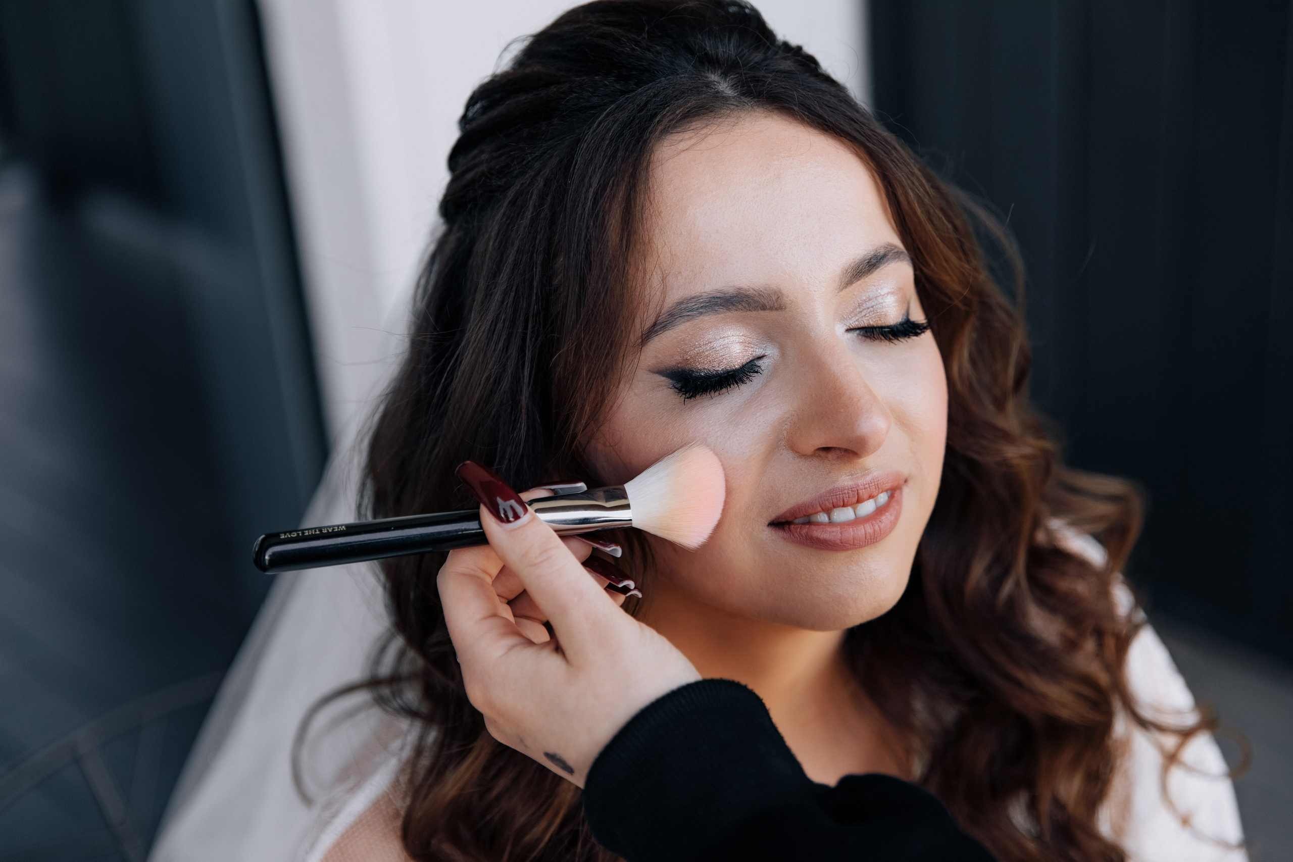 Die Braut wird mit einem Pinsel geschminkt. Ein intimer Moment der Hochzeitsvorbereitungen.