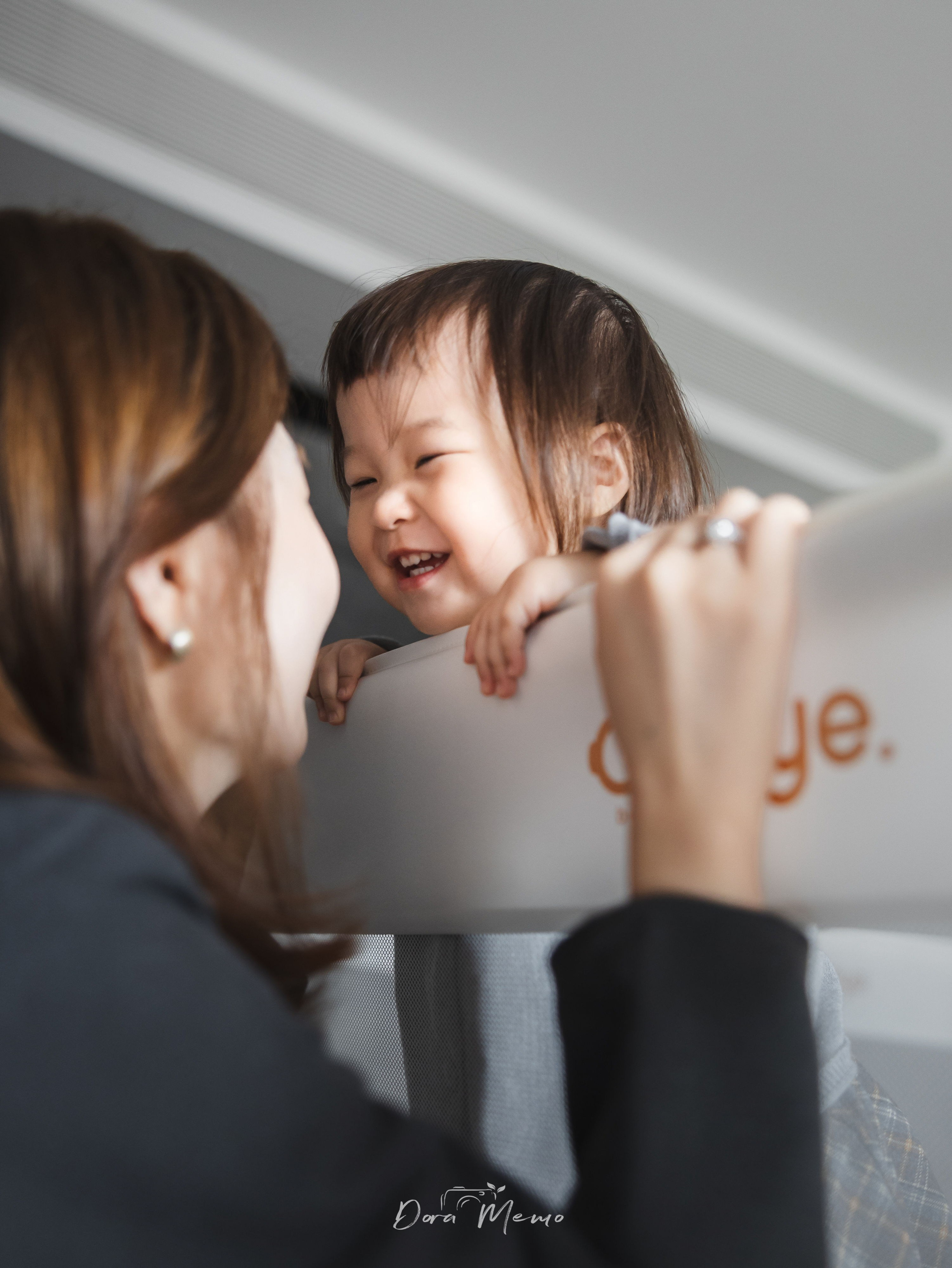 Mother and daughter playing together by the bed, everyday family moment captured naturally in their Shanghai home.