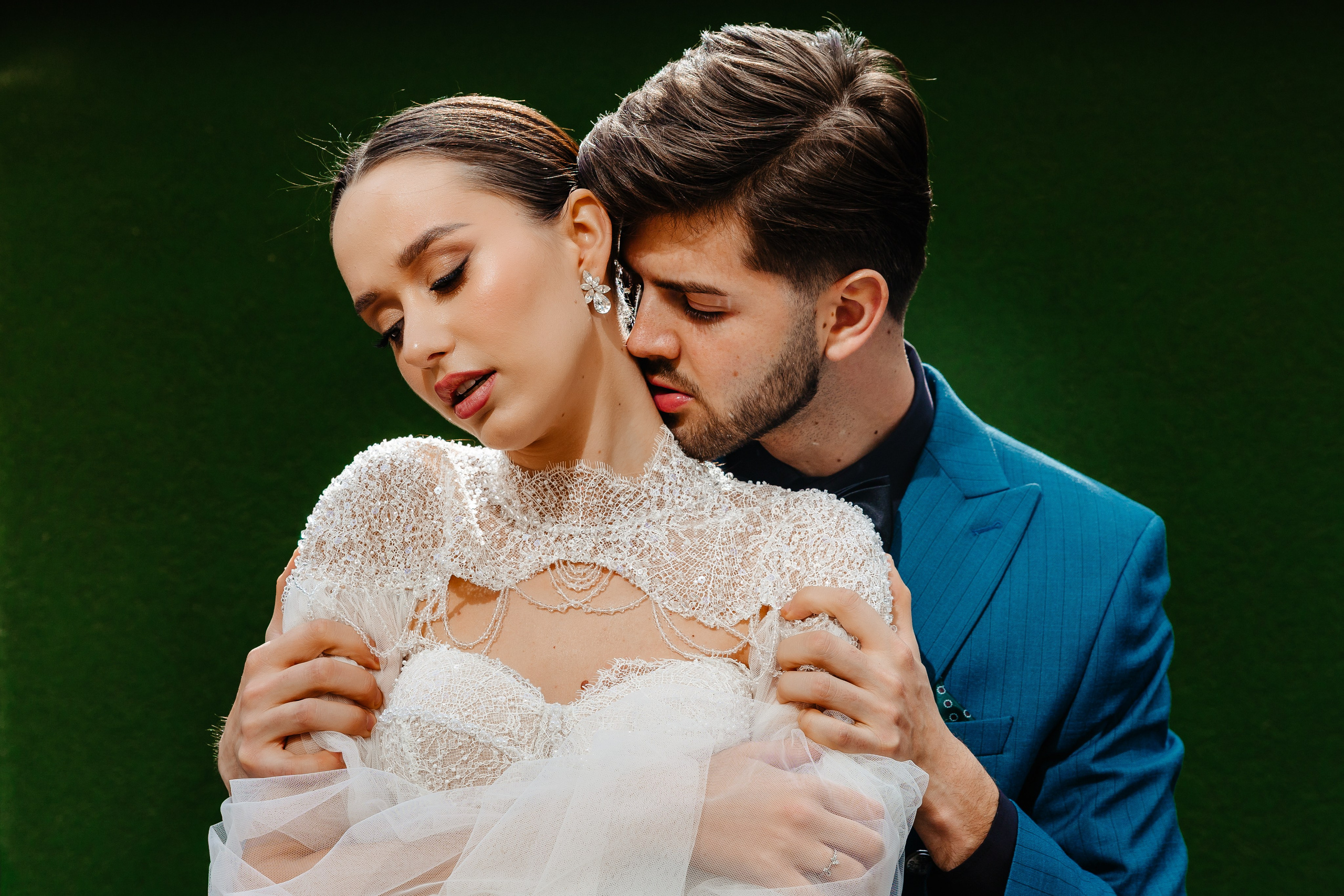 Mirele și mireasa îmbrățișați, cu fundal verde profund