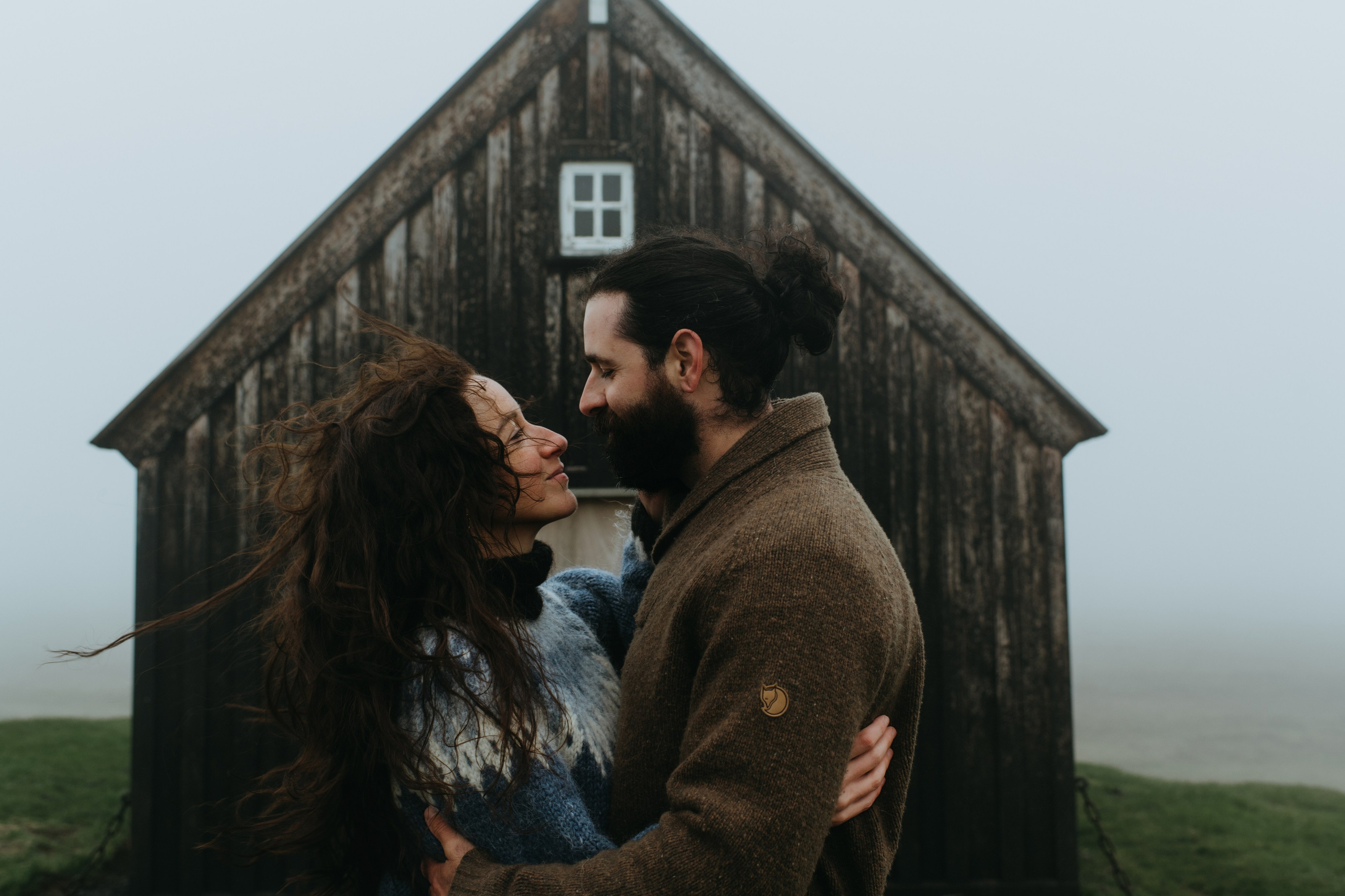 Bride and groom standing in front of the historic Krýsuvíkurkirkja, with dark clouds adding to the dramatic atmosphere.