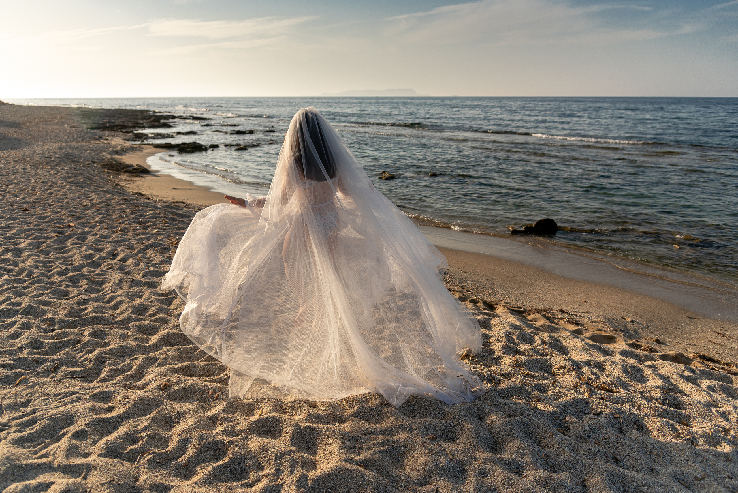 A girl in a wedding dress runs along a sandy beach Photographer in Crete