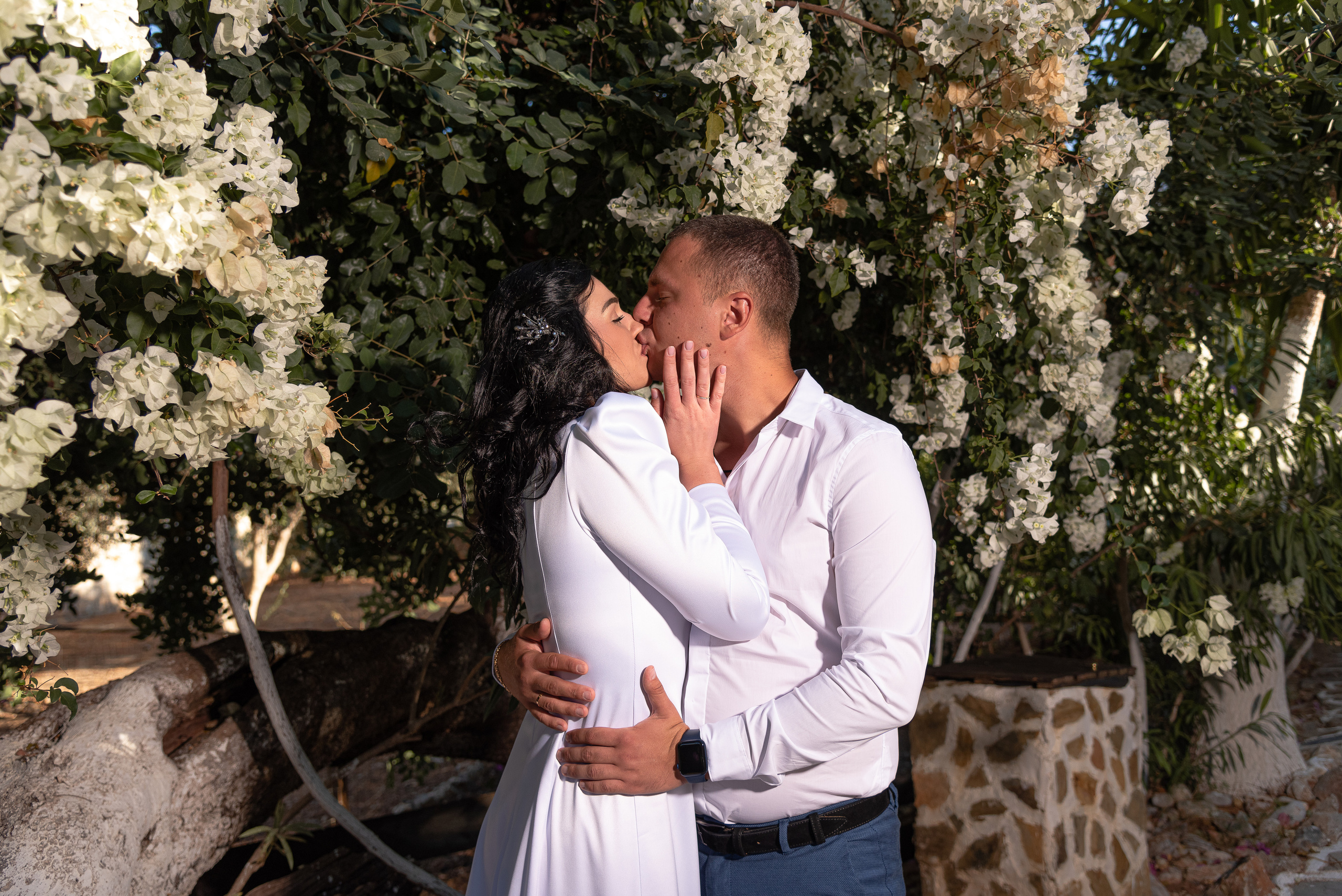 The newlyweds kiss against the background of white oleander
