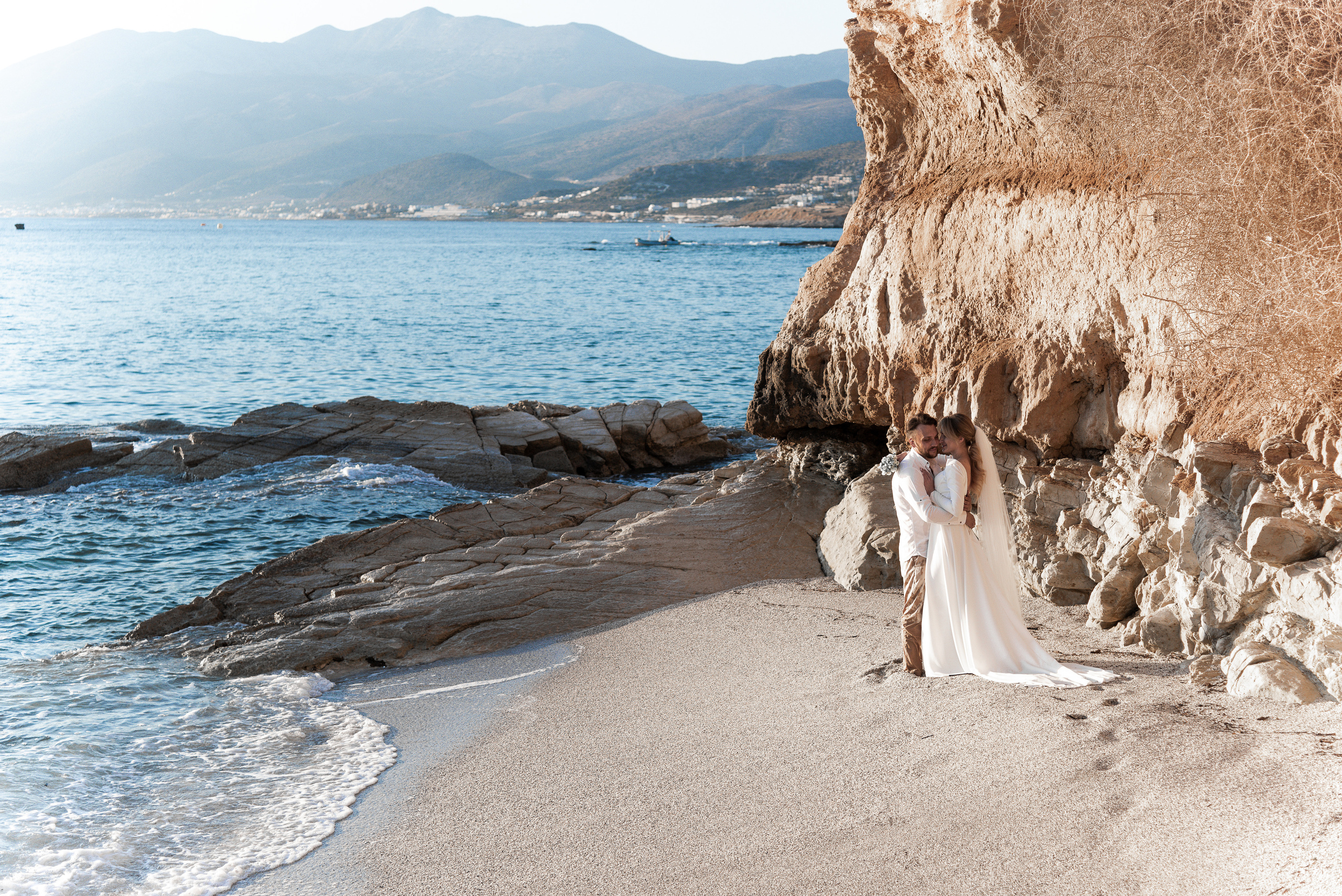 Wedding photo shoot in Crete by the sea on the background of rocks