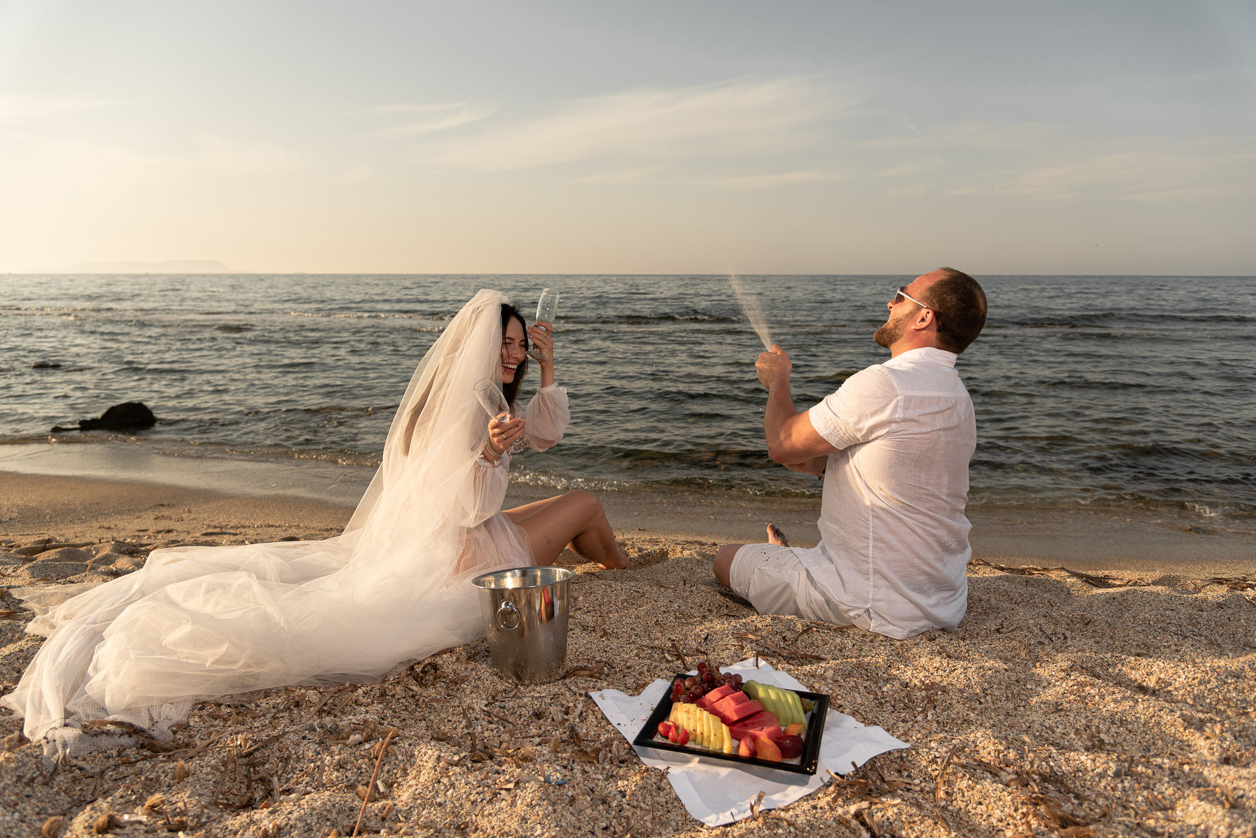 Wedding photographer in heraklion couple open champagne and eat fruit