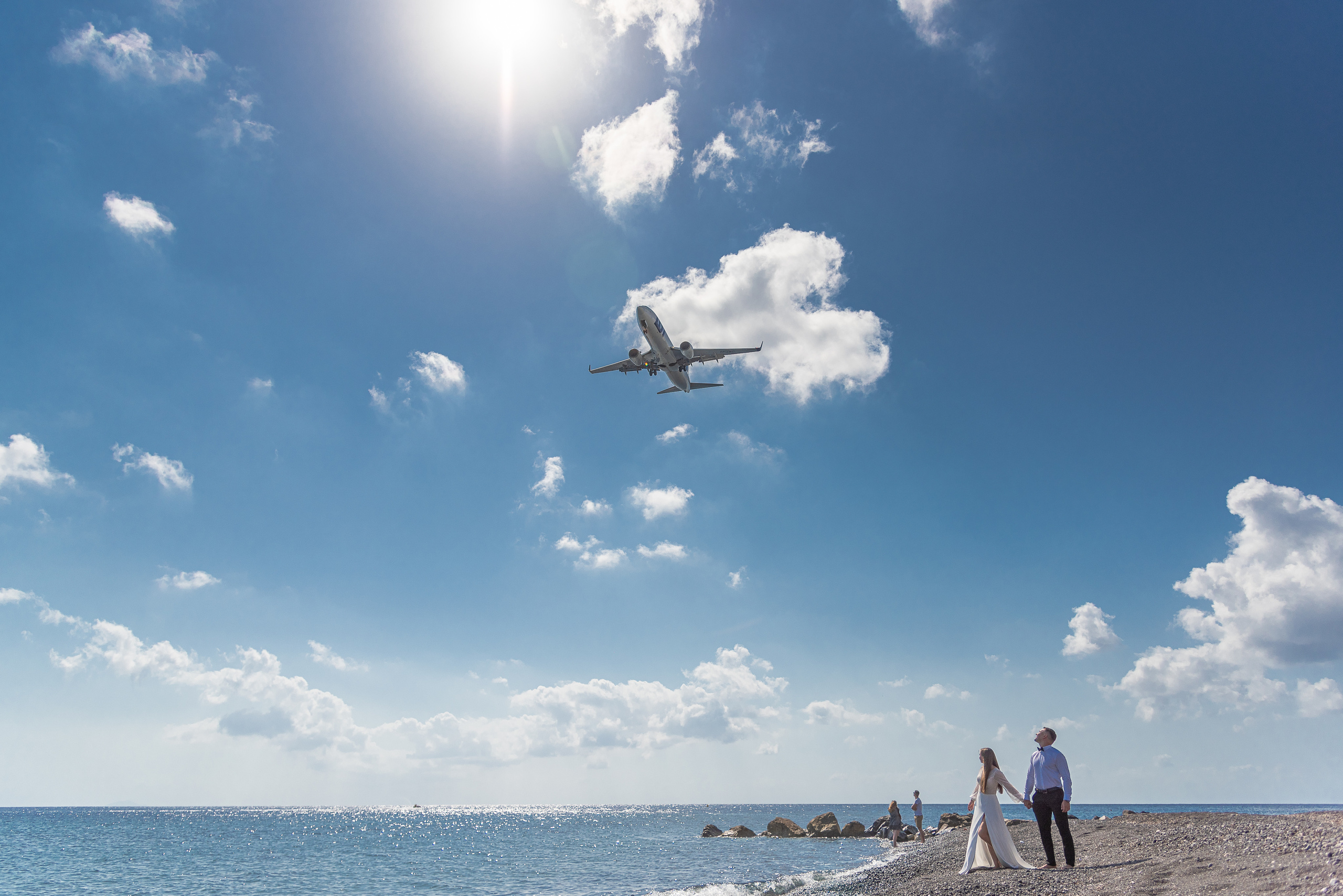 A couple walks along the seashore and flies a plane to Santorini