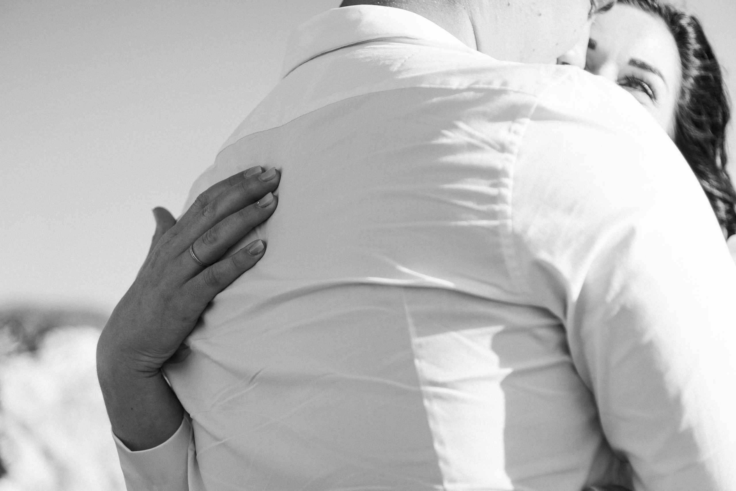 The newlyweds are standing on a mountain with a view of the sea and hugging