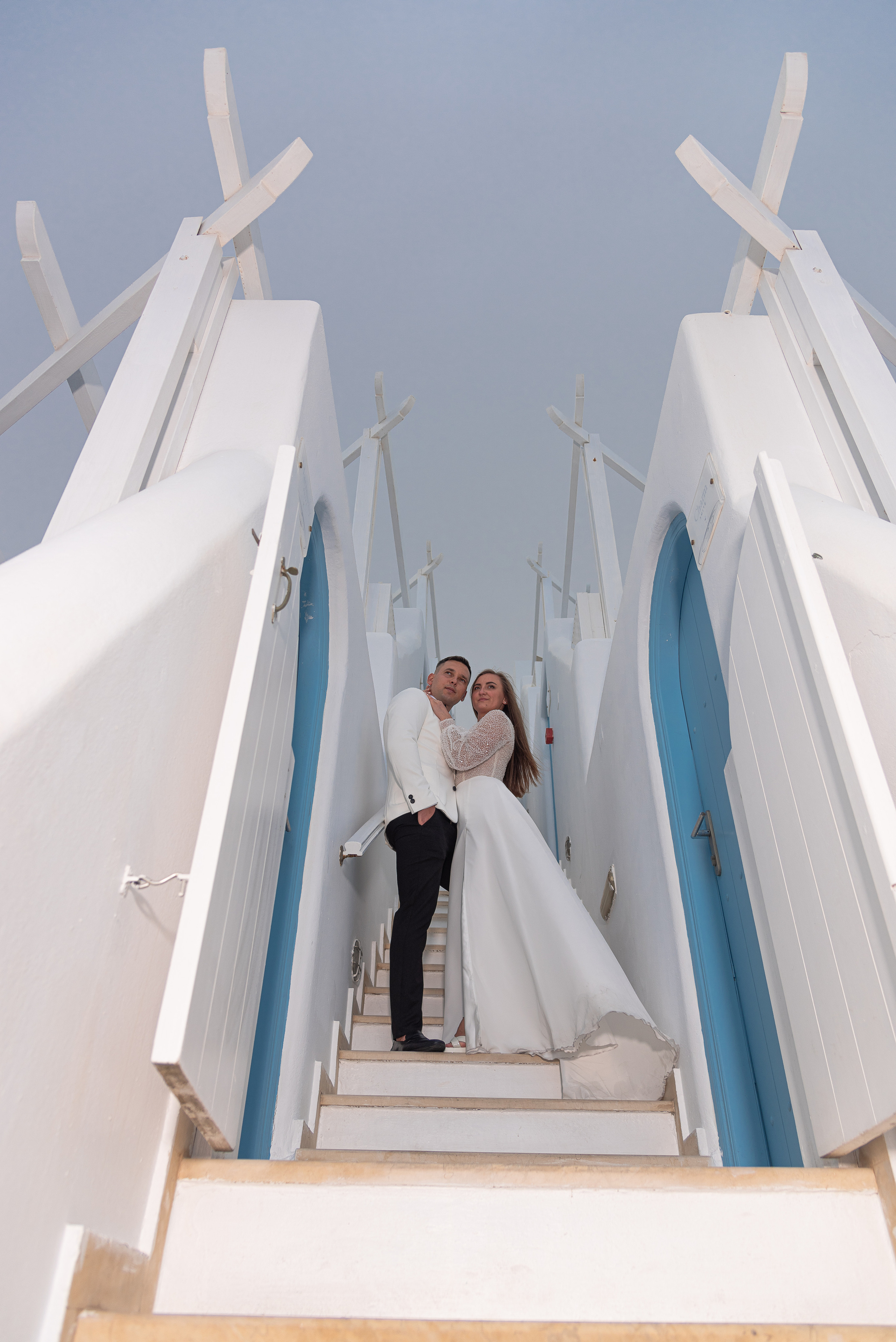 The bride and groom are standing on the stairs to the sky in Santorini
