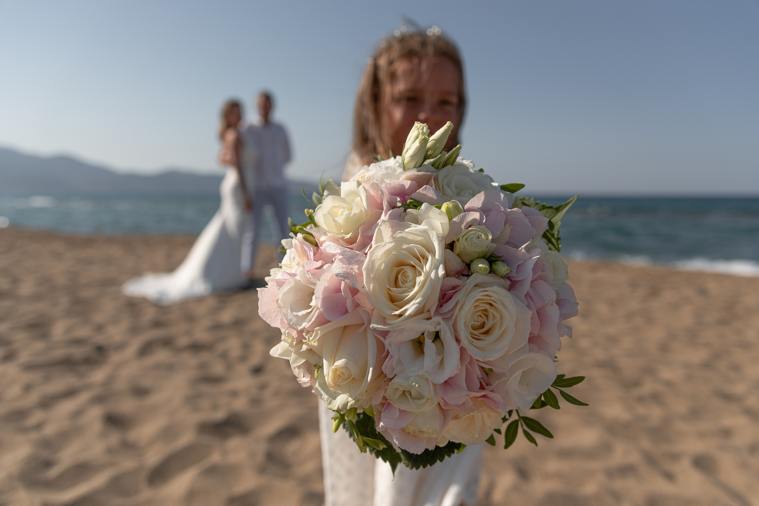 Wedding photo shoot in Heraklion on the beach a child holds a bouquet of the bride
