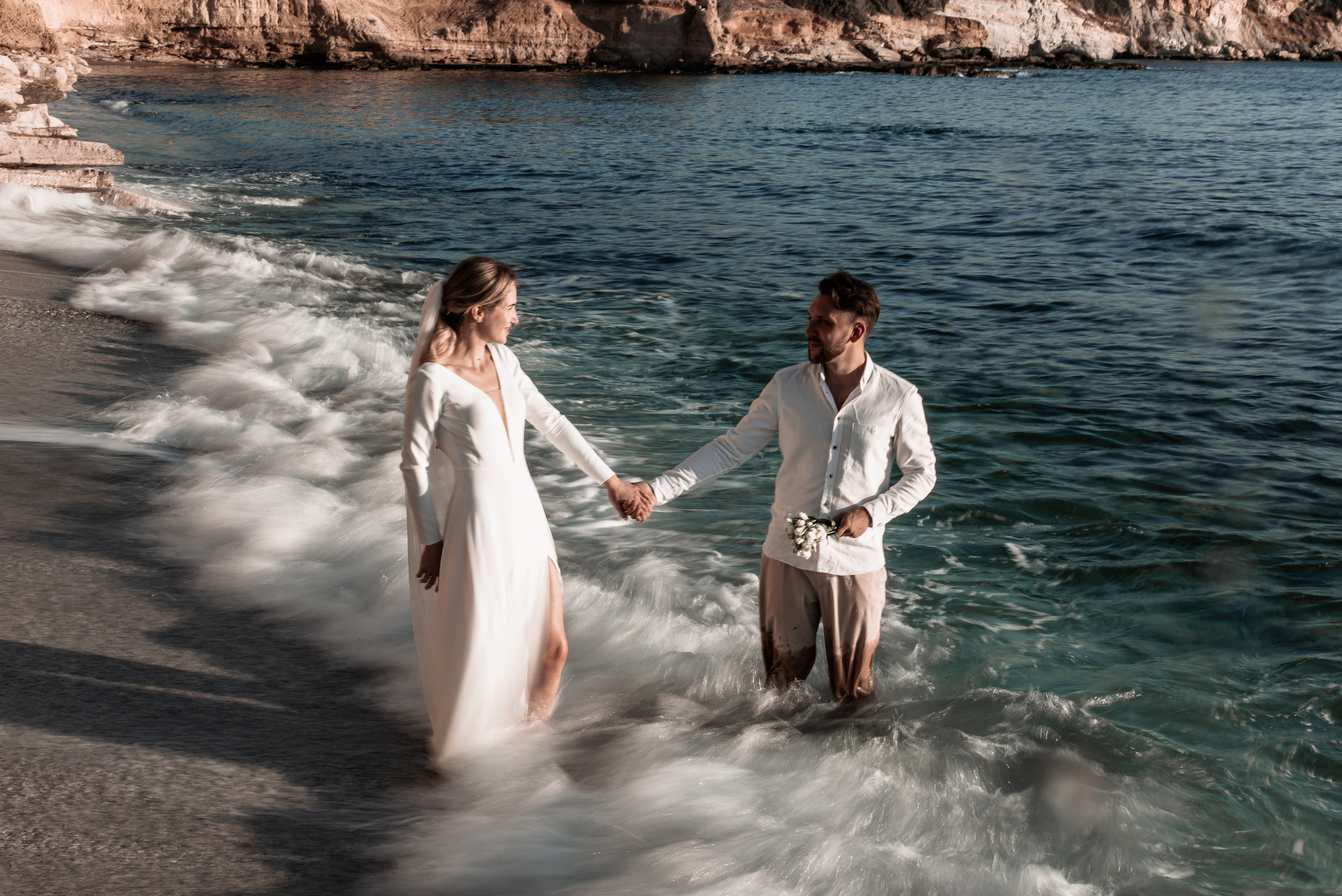 A couple in wedding suits is standing in the sea