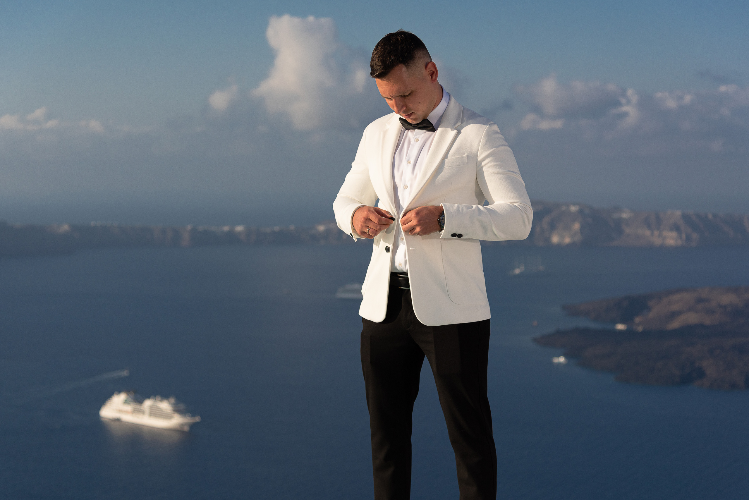 The groom in a white jacket is going to a wedding in Santorini
