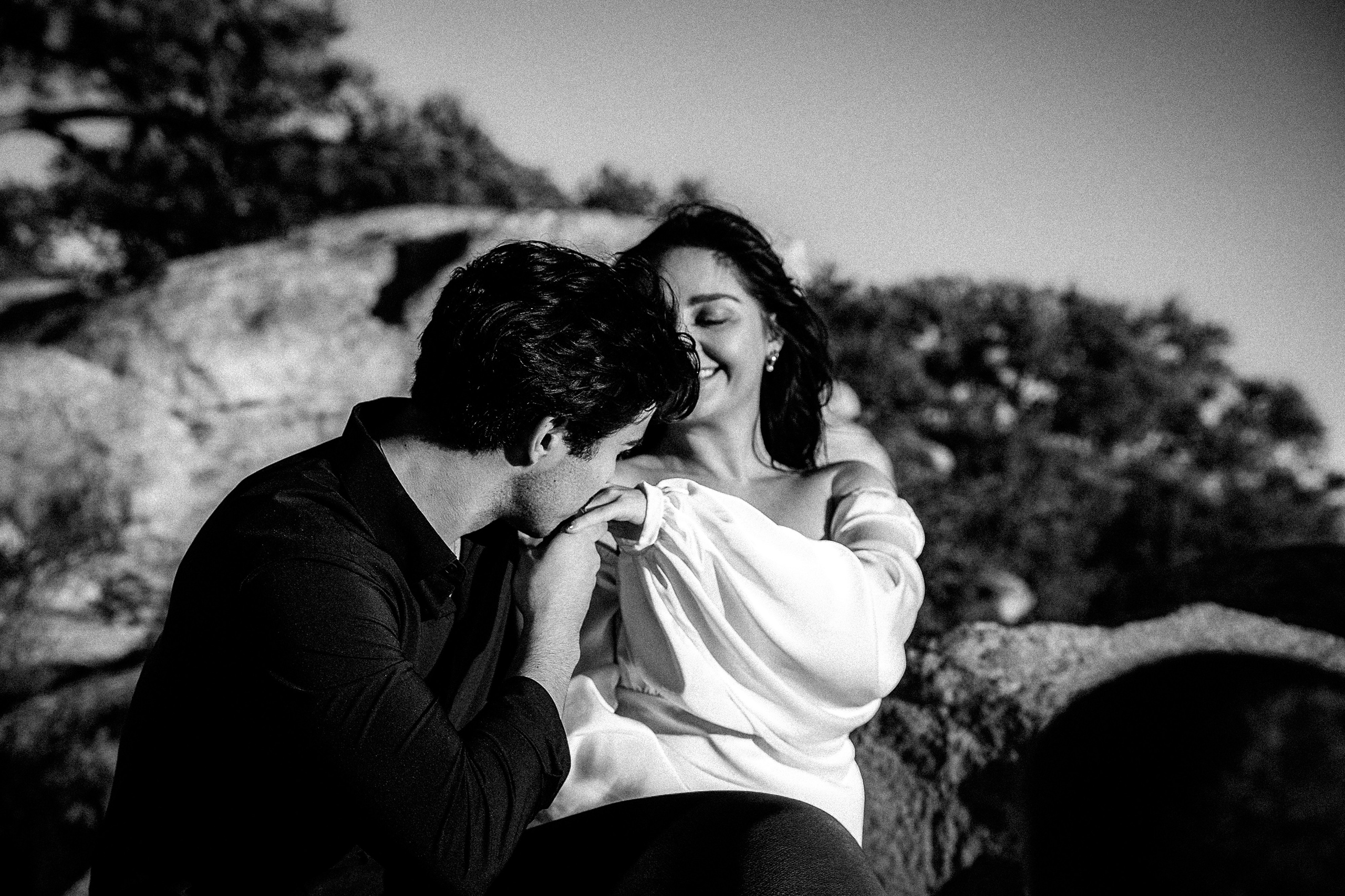 Bride and groom sitting together on rocky terrain during a sunset destination elopement in Barcelona, Spain. This intimate wedding portrait captures the peaceful atmosphere of a private mountain ceremony and romantic engagement story.