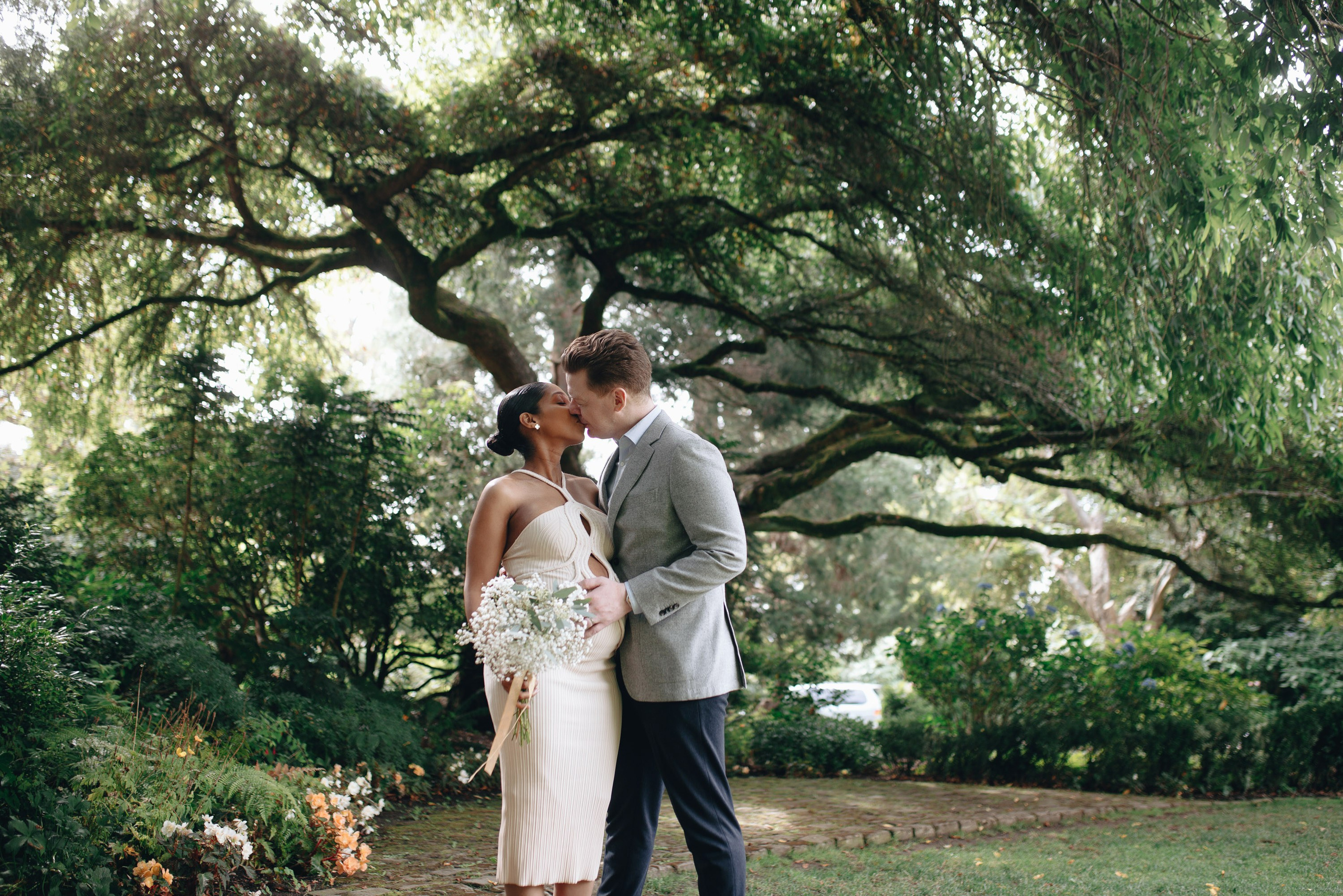 Wedding couple standing under tree, garden ceremony