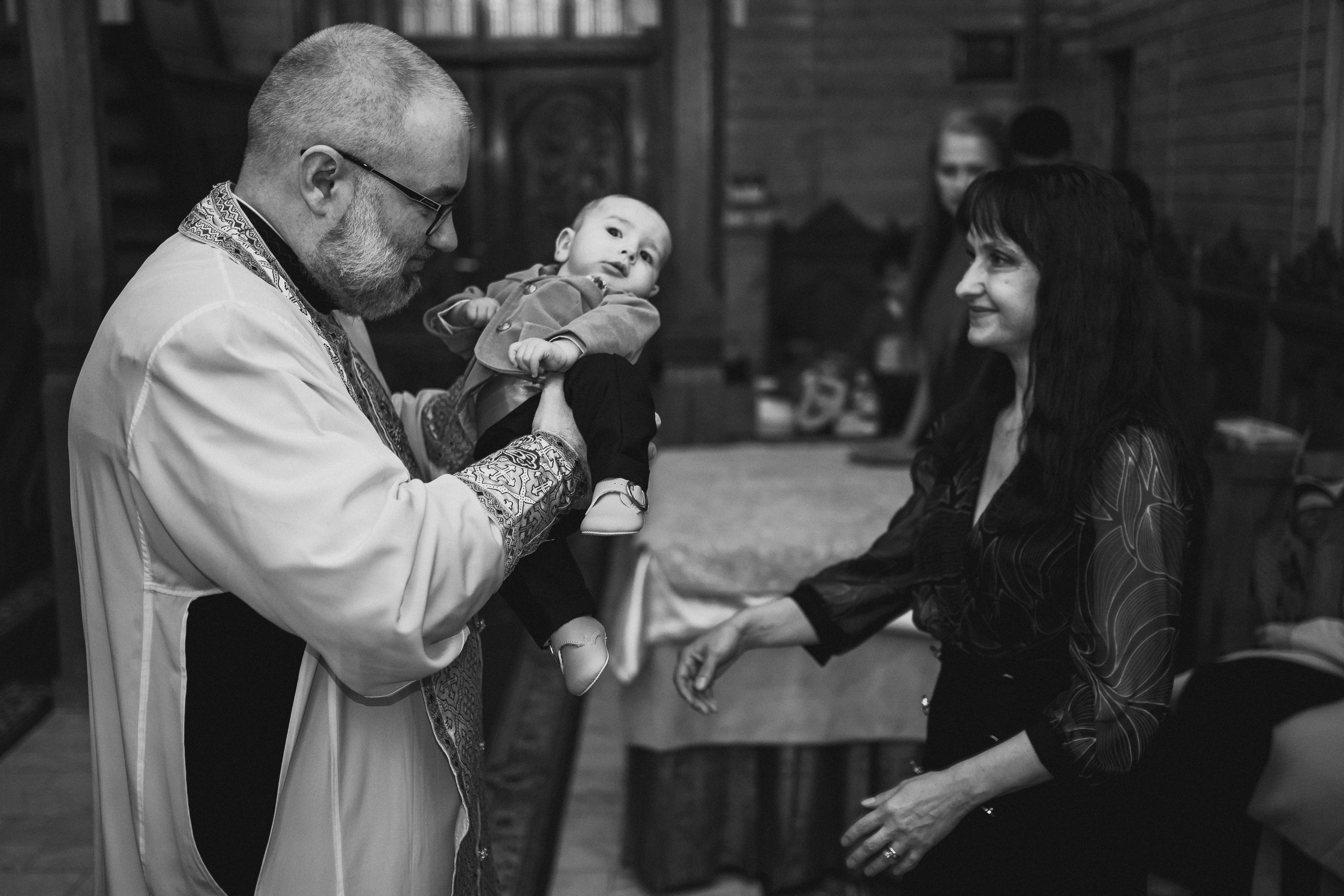 Instantaneu plin de tandrețe dintre părinți și bebeluș în ziua botezului, realizat în Bucuresti. Fotografie profesională de botez, capturând emoțiile autentice ale familiei într-un decor luminos și cald