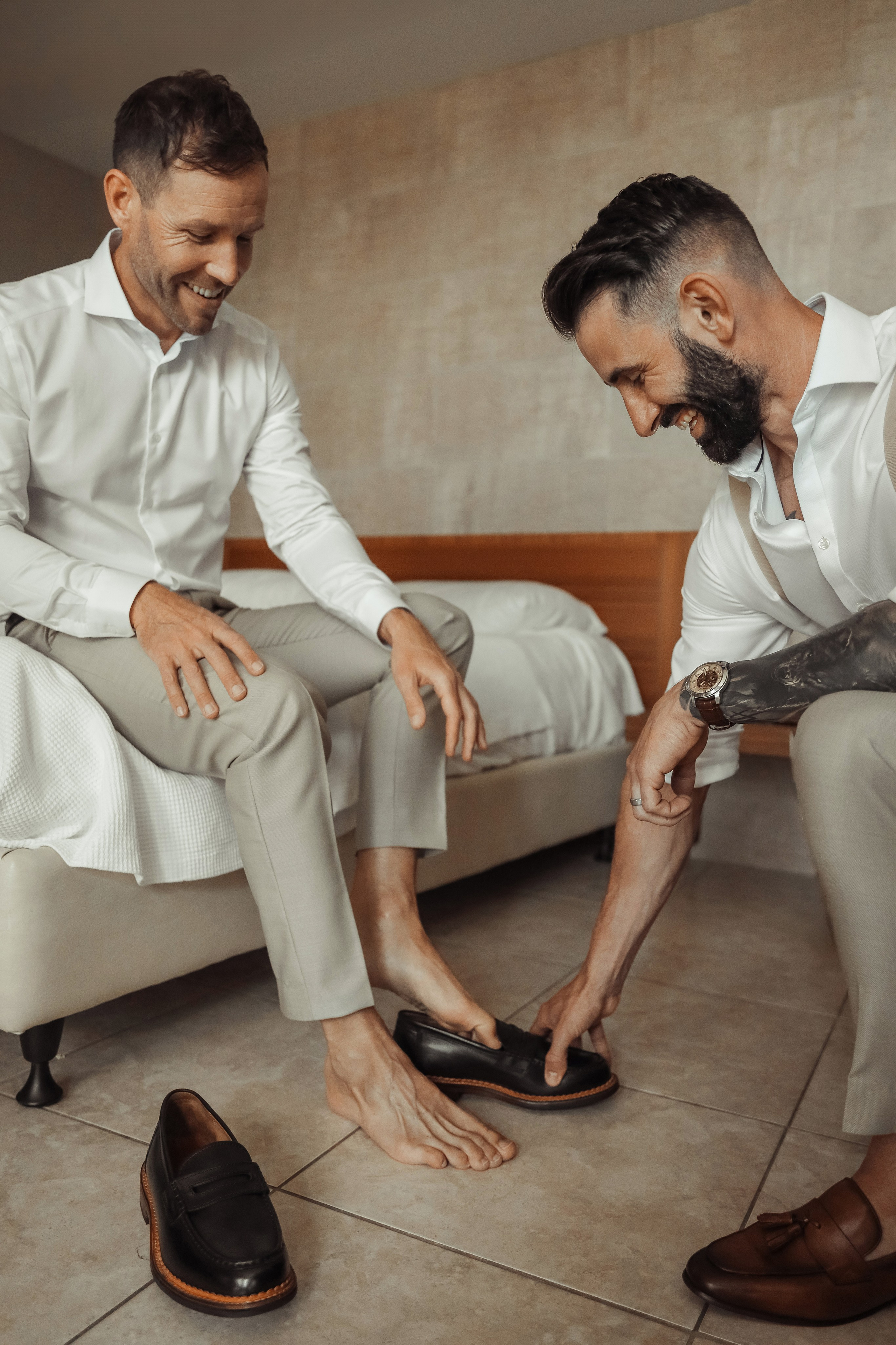 The groom preparing for his wedding day, with close friend putting the shoes in a relaxed and joyful atmosphere. Rhodes, Greece
