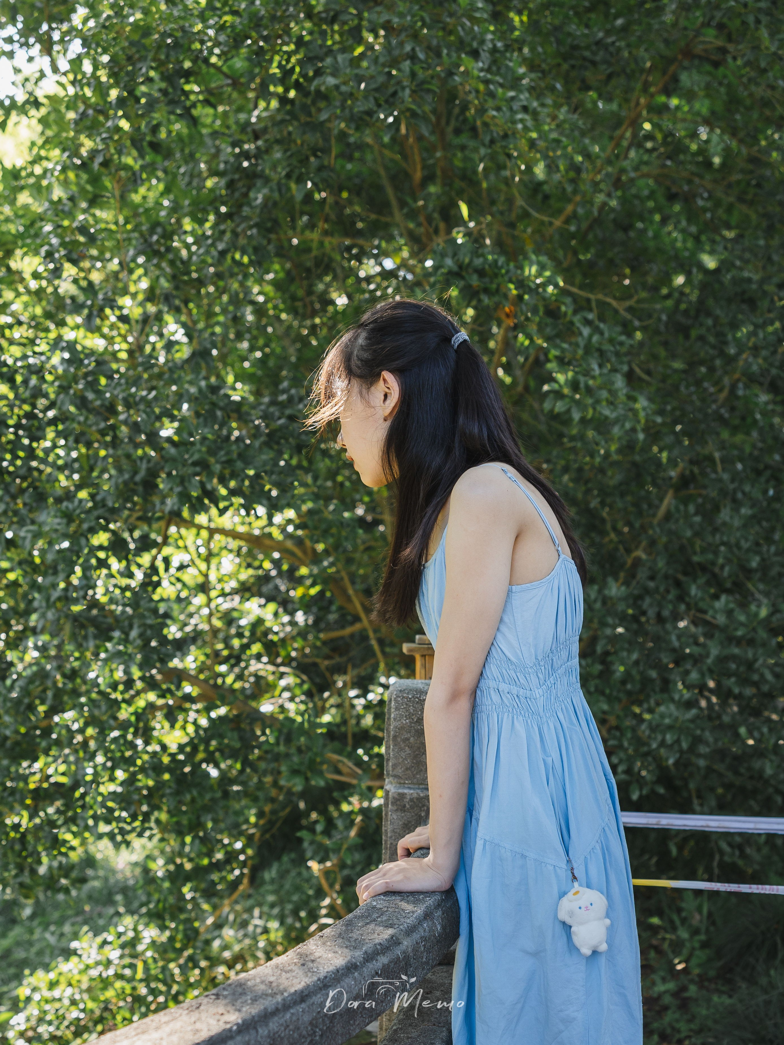 Leaning on a railing, looking down, backlit glow | A teenage girl leaning on a railing, soft backlight creating a gentle halo