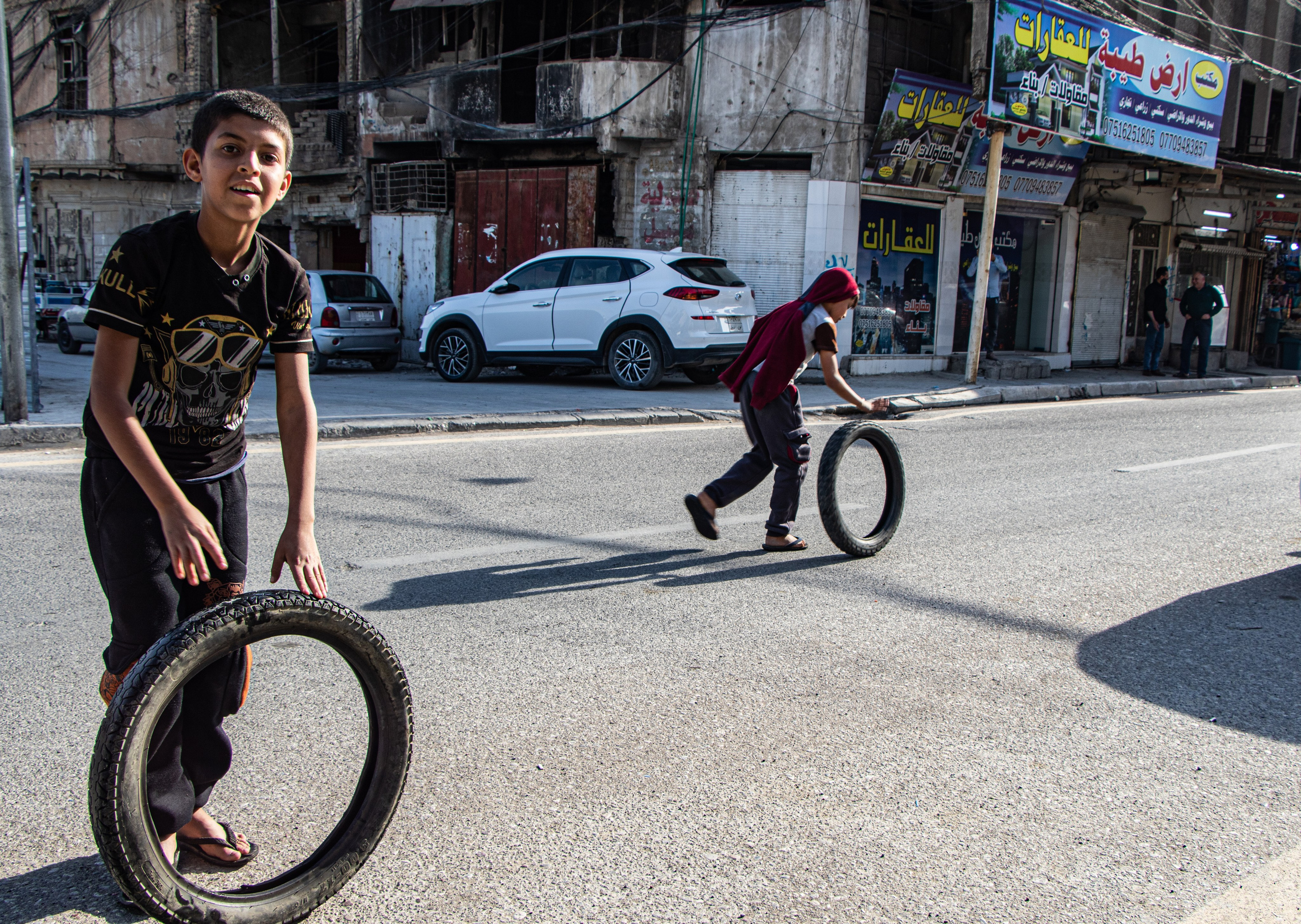 Des jeunes garçons jouent avec des pneus dans les rues de Mossoul.