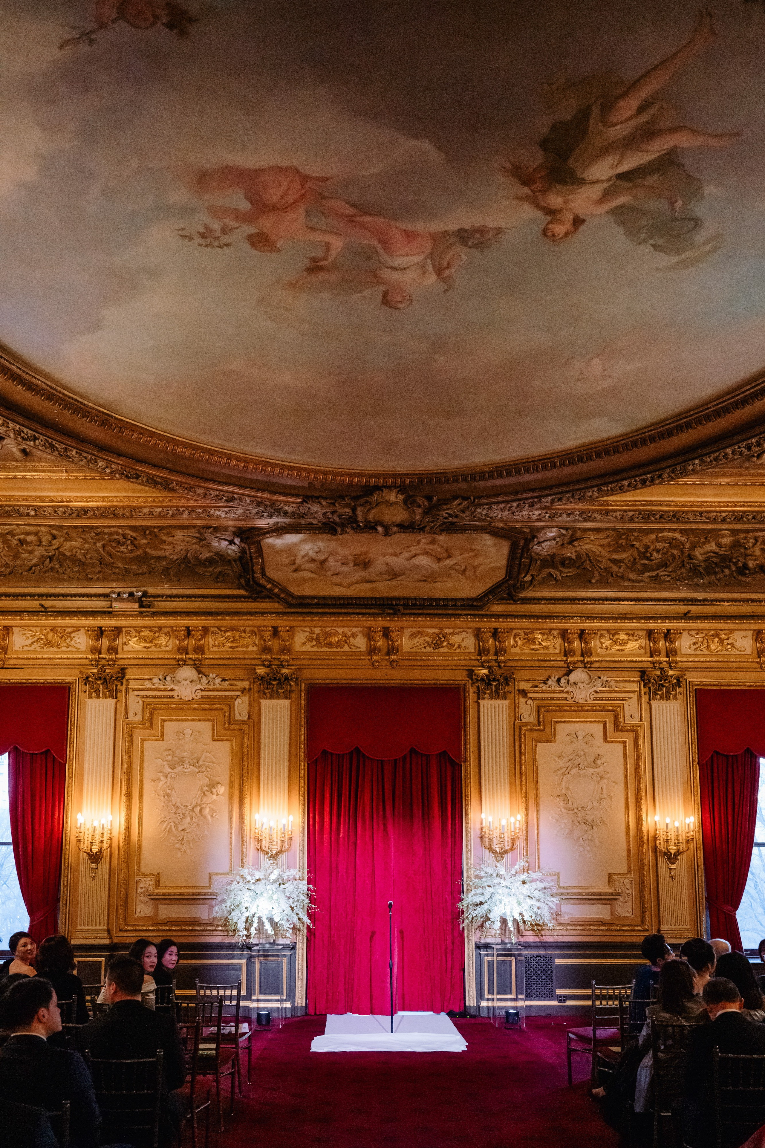 a room with a red curtain and a painting on the ceiling