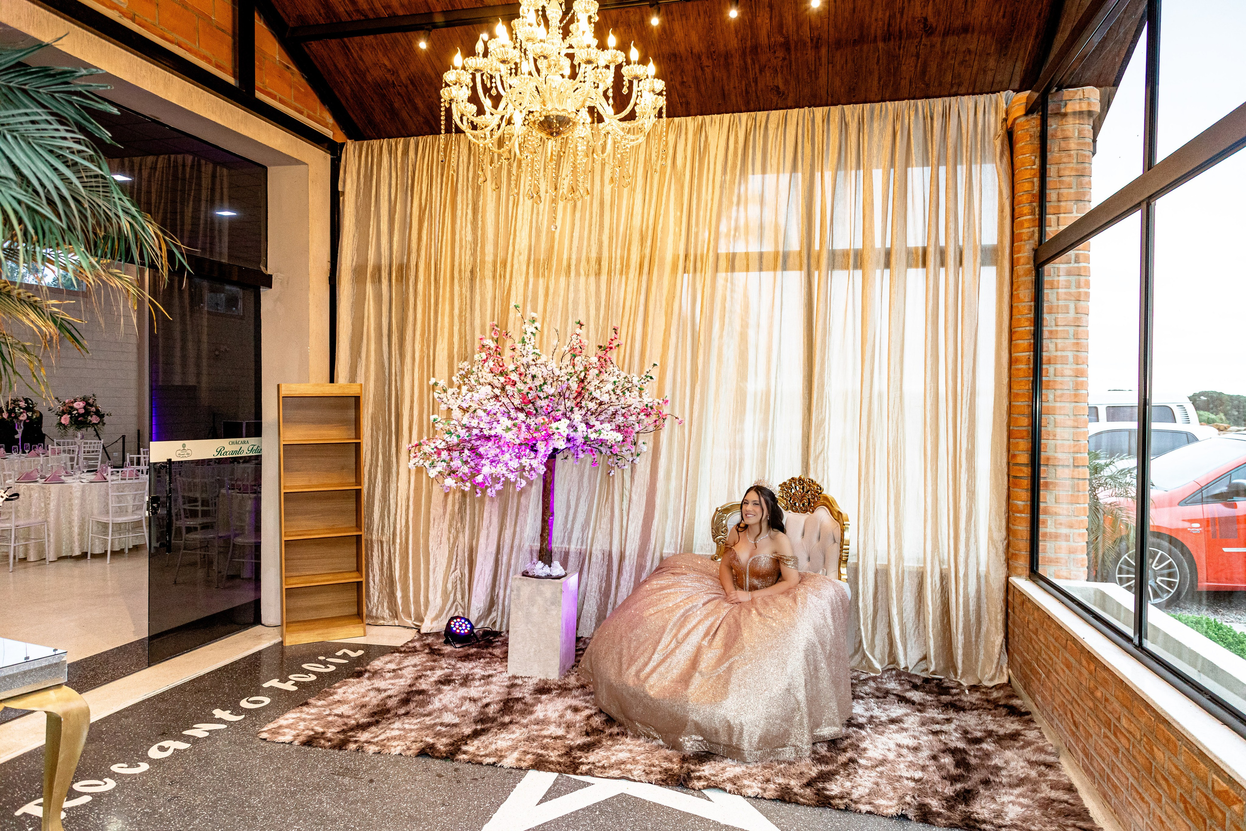 espaço de luxo com a myrella sentada com seu lindo vestido dourado