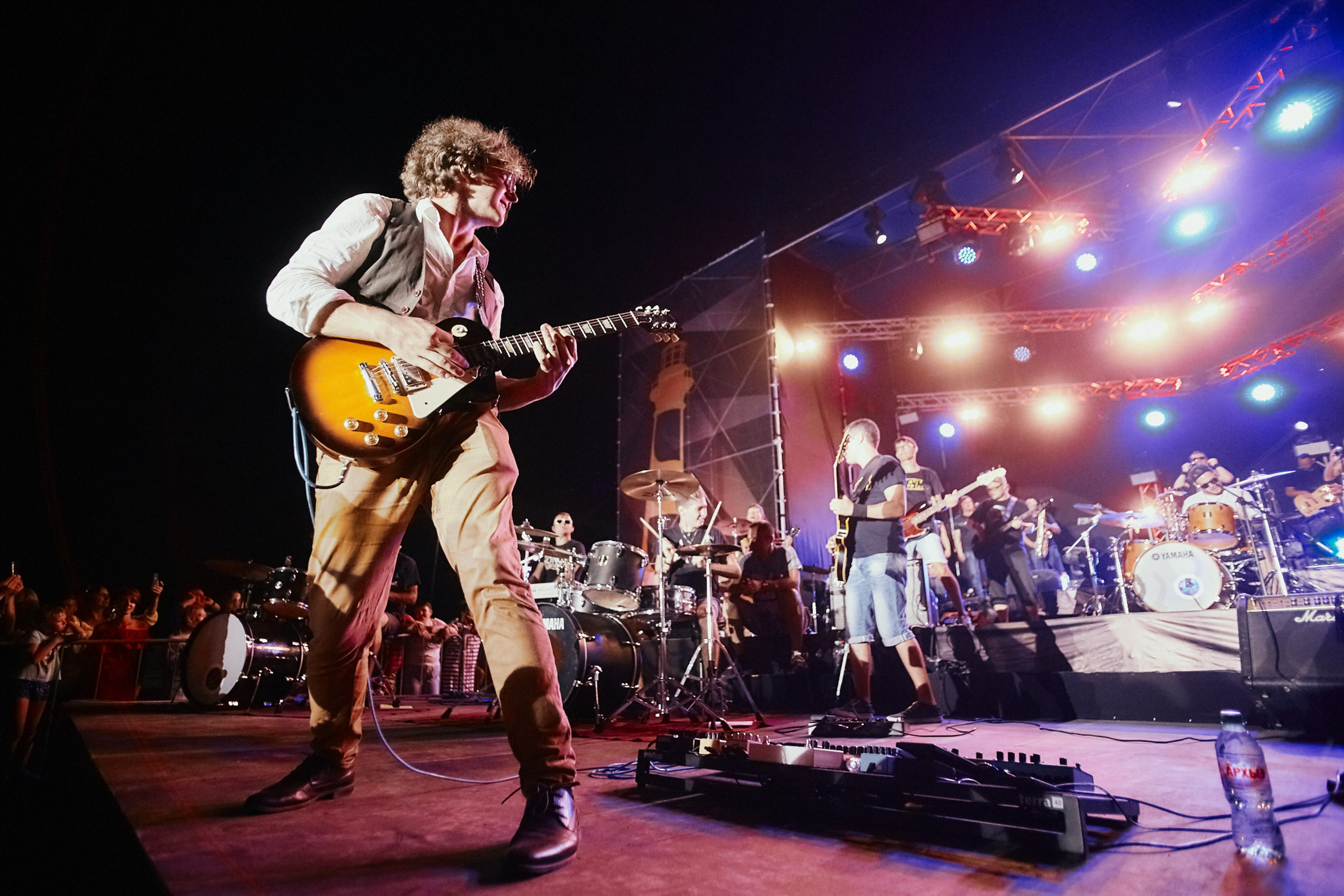 Guitarist performing on stage with a band under stage lights
