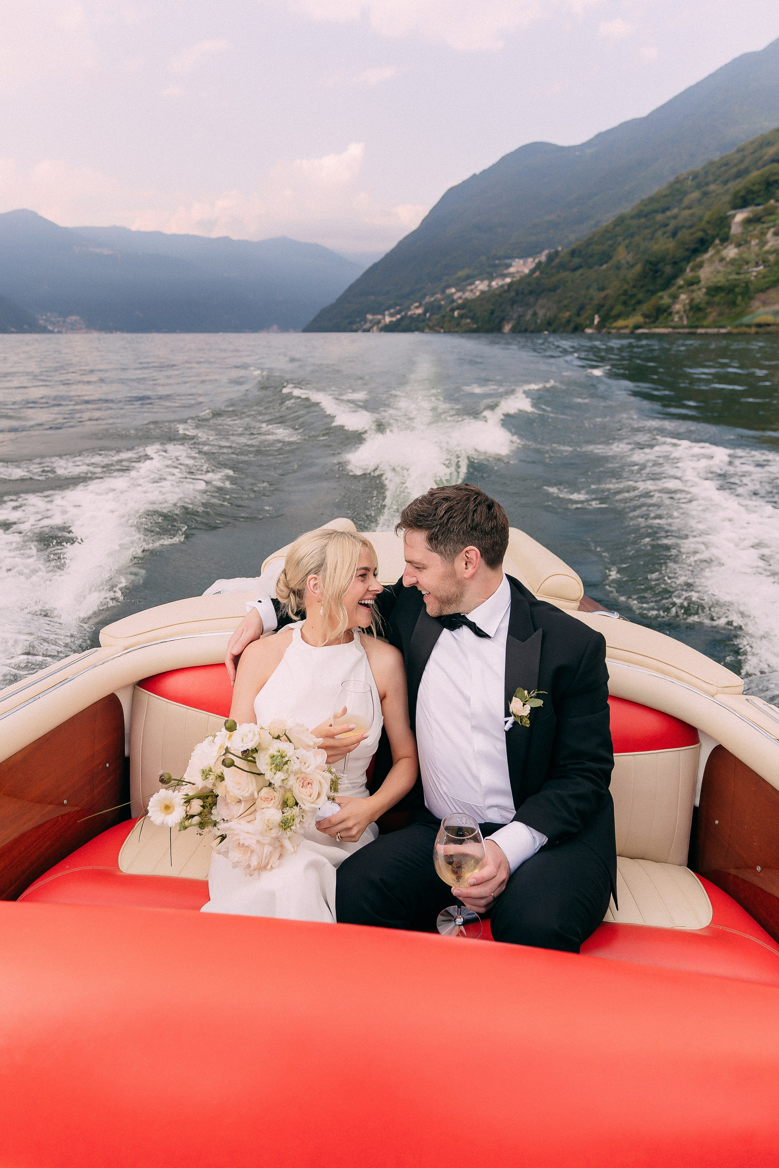Bride and groom embracing on the moving boat at Villa Lario, Lake Como, Italy