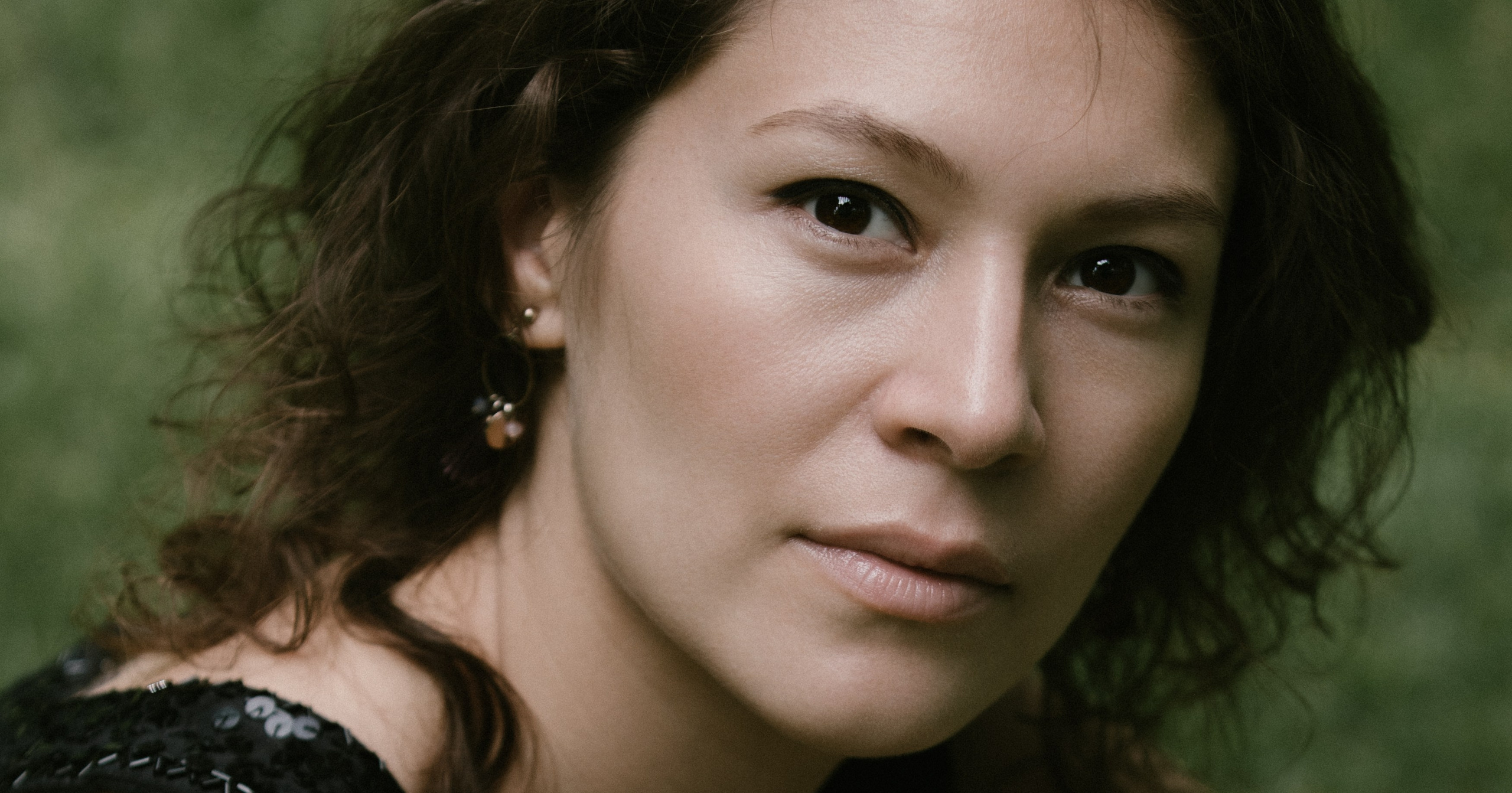 Porträt mit direktem Blick, Naturlicht und grünem Hintergrund