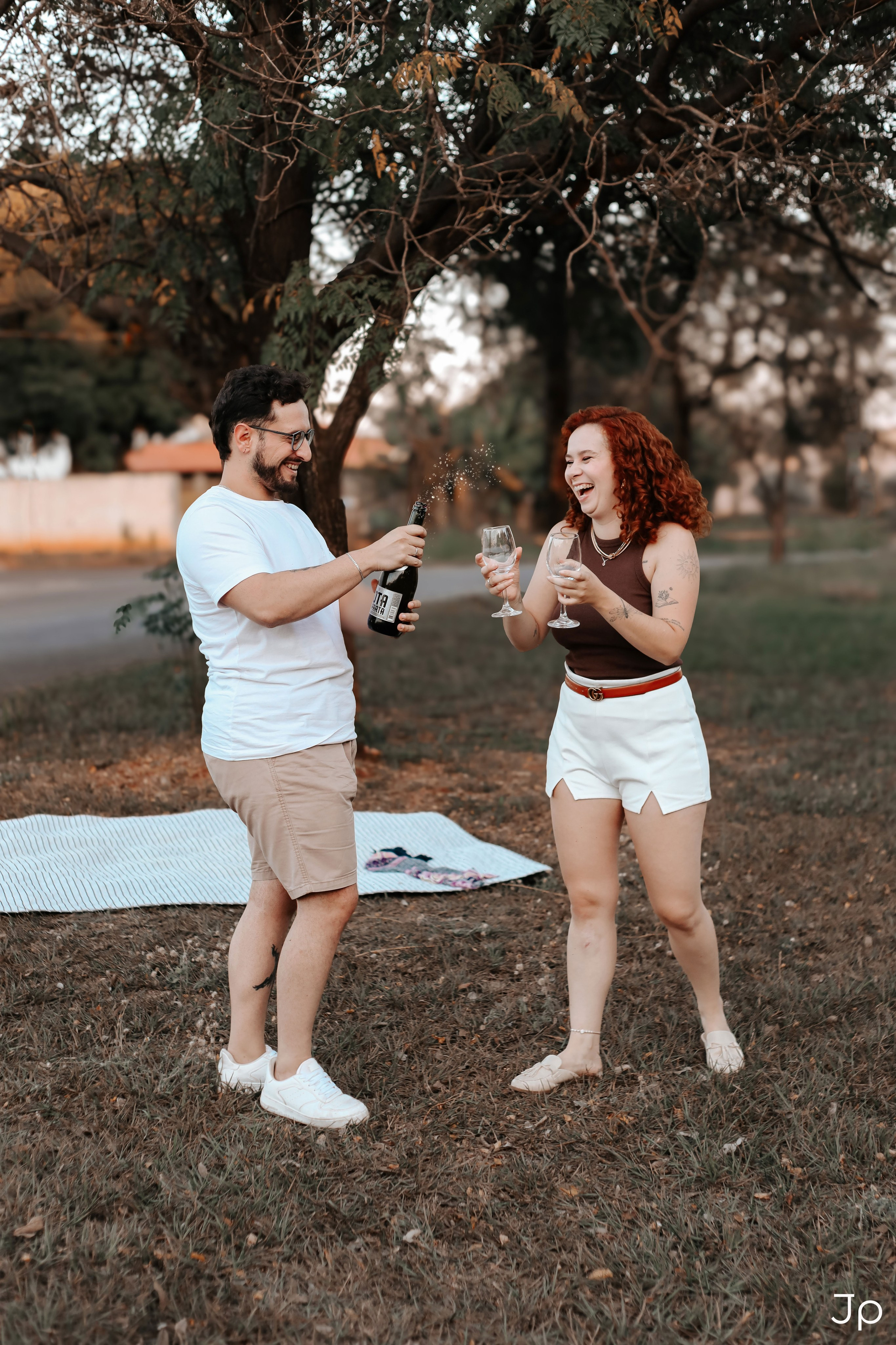 Casal se divertindo ao abrir a bebida no piquenique.