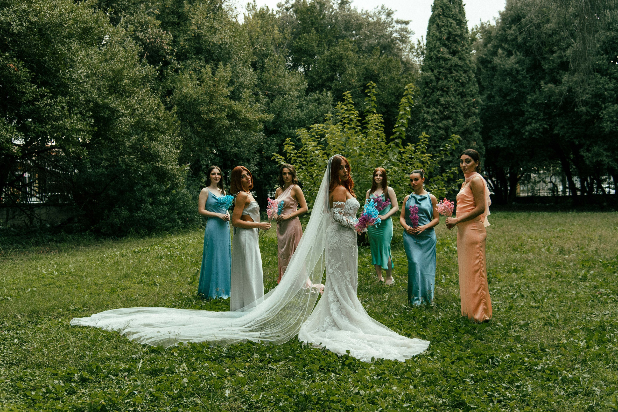 Bride and bridesmaids posing together in a lush forest setting