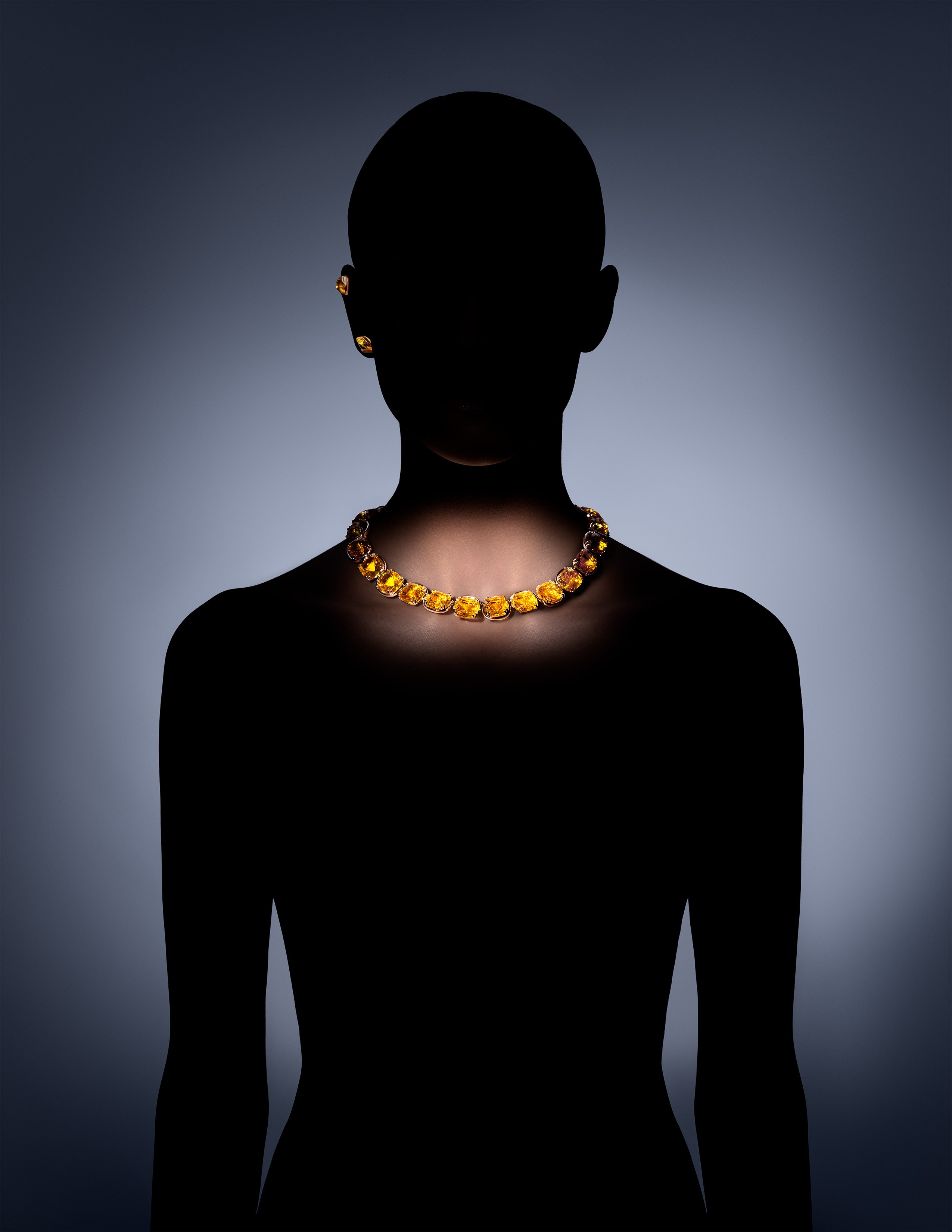 Minimalist fashion portrait featuring a Swarovski yellow gemstone necklace glowing against a dramatic silhouette – luxury jewelry for elegant styling.