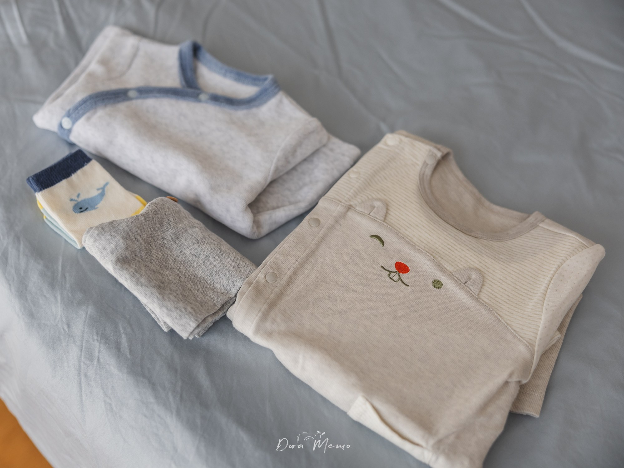 Tiny baby clothes laid on a bed during a Shanghai maternity photo session at home.