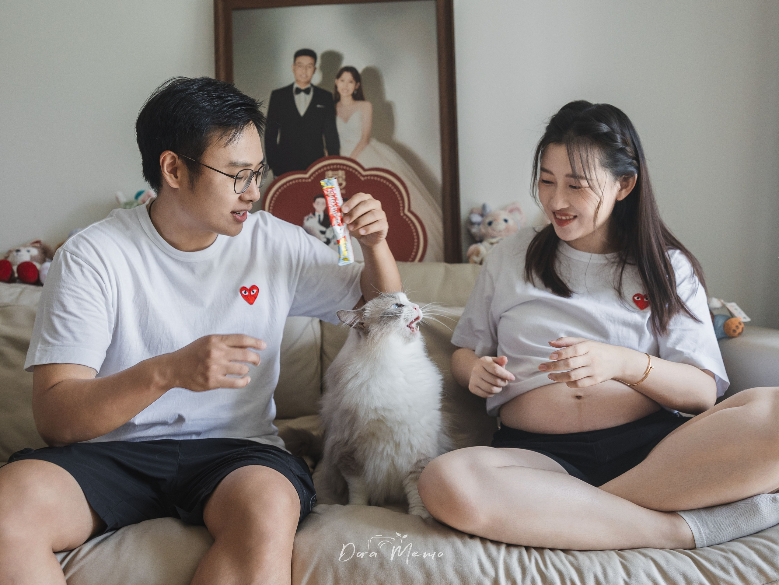Parents-to-be sit on the sofa with their Ragdoll cat during a relaxed Shanghai family photography session.