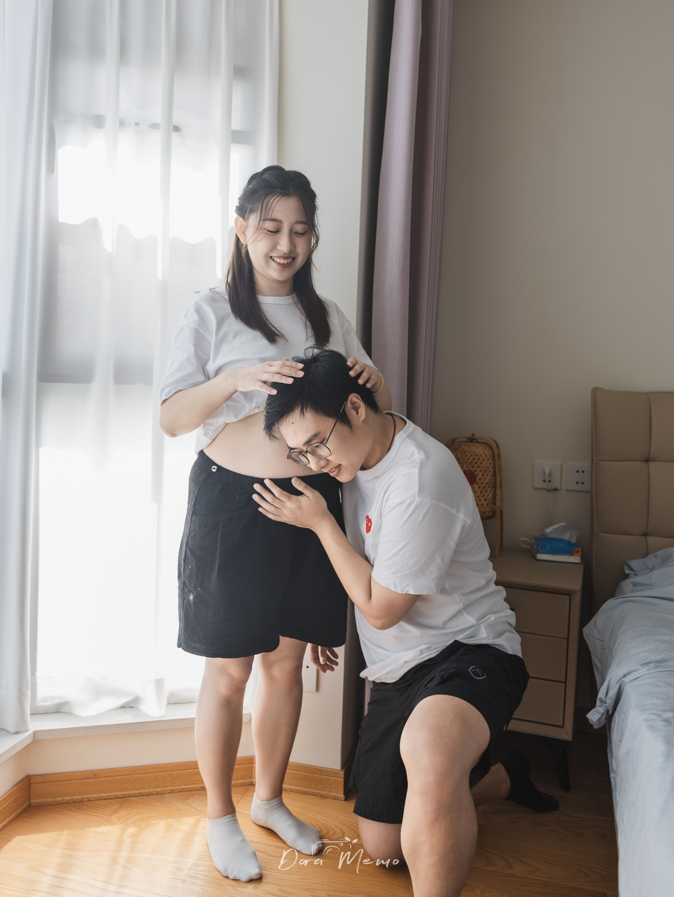  An expecting father kisses the mother’s belly in a quiet at-home maternity portrait.