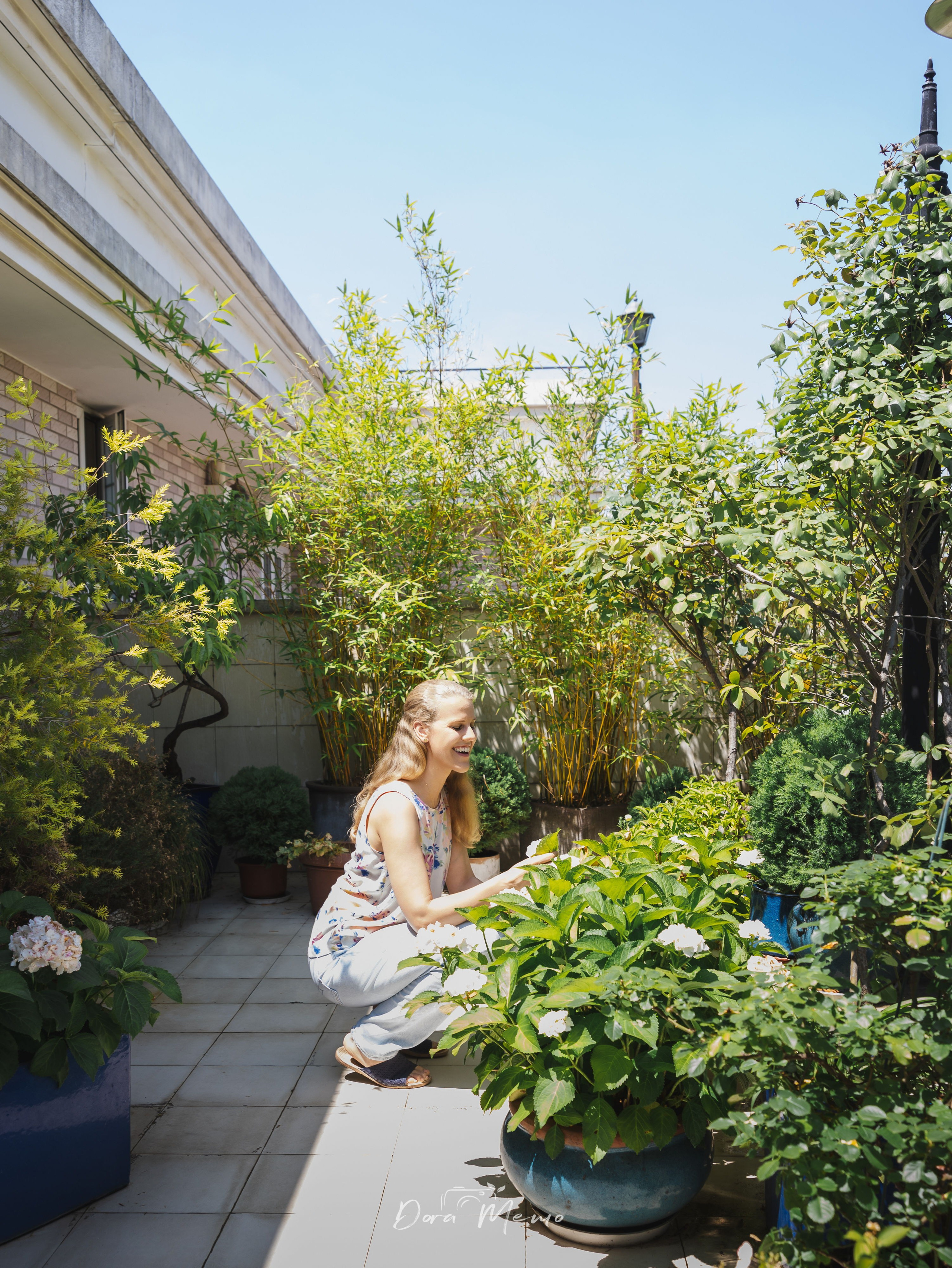 A daughter standing among terrace plants and bougainvillea at her family home in Shanghai.