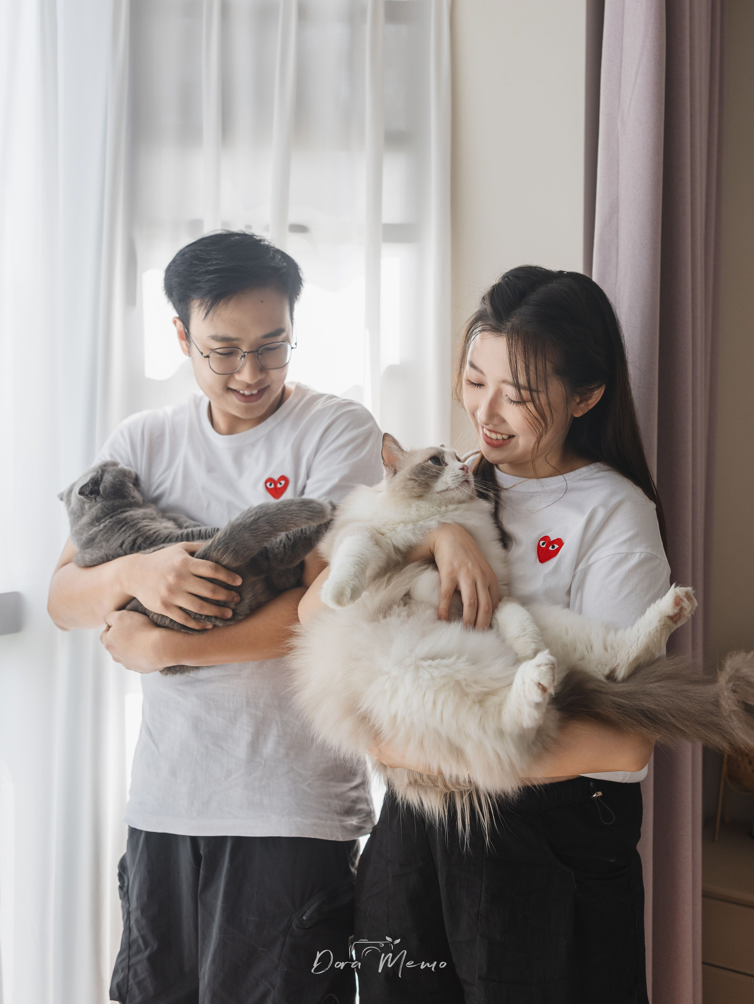 Expecting parents hold their two cats for a warm family portrait at home in Shanghai.
